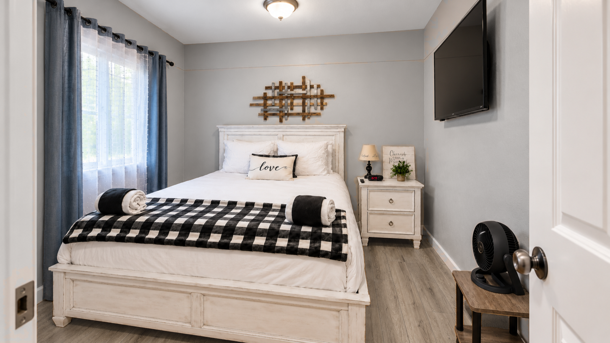 Cozy, bright bedroom with TV, stylish decor, and inviting bedding