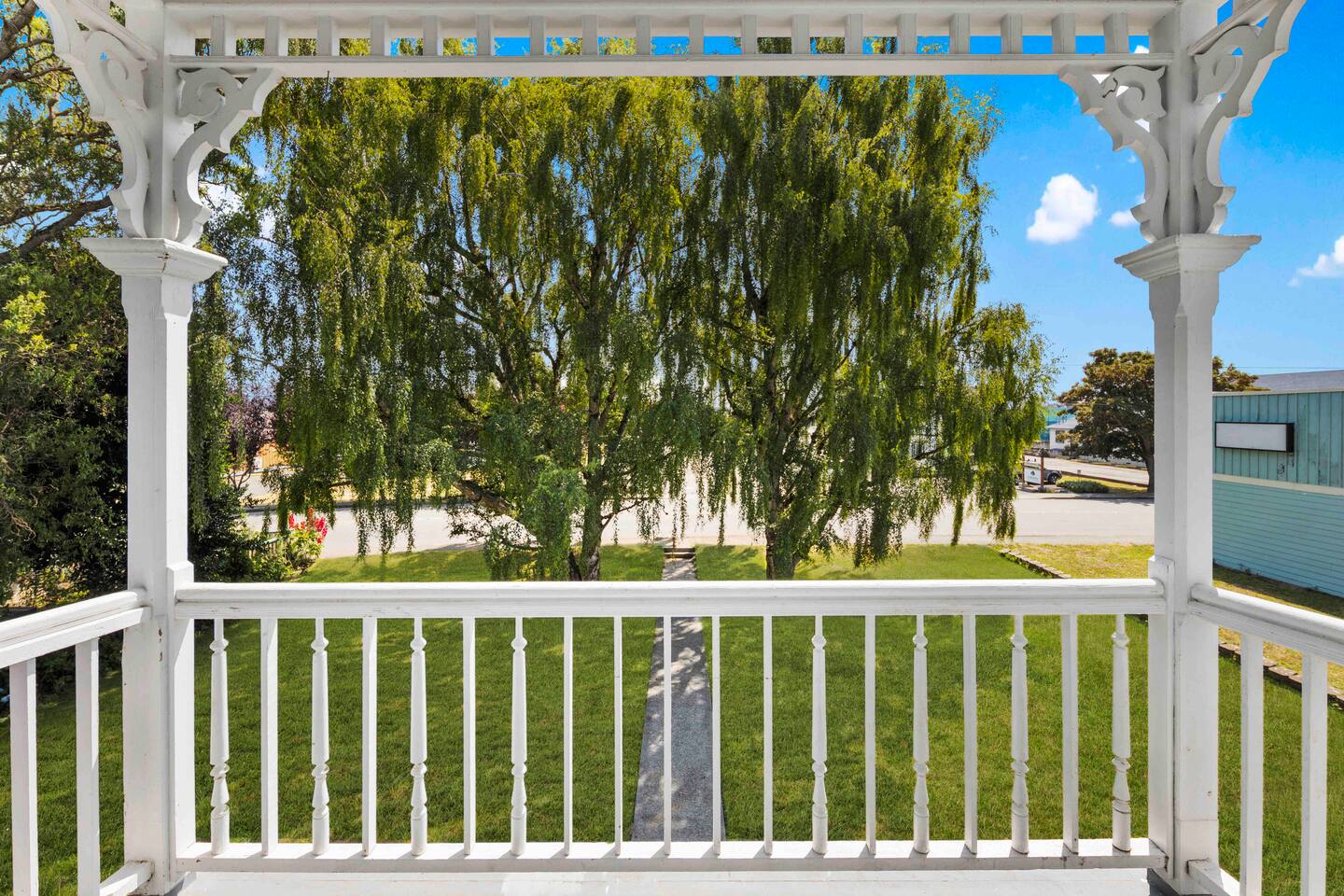 Charming balcony with intricate Victorian woodwork and lush willow views. A peaceful spot to enjoy morning coffee while you meditate or an evening glass of wine, offering a perfect blend of elegance and tranquility.