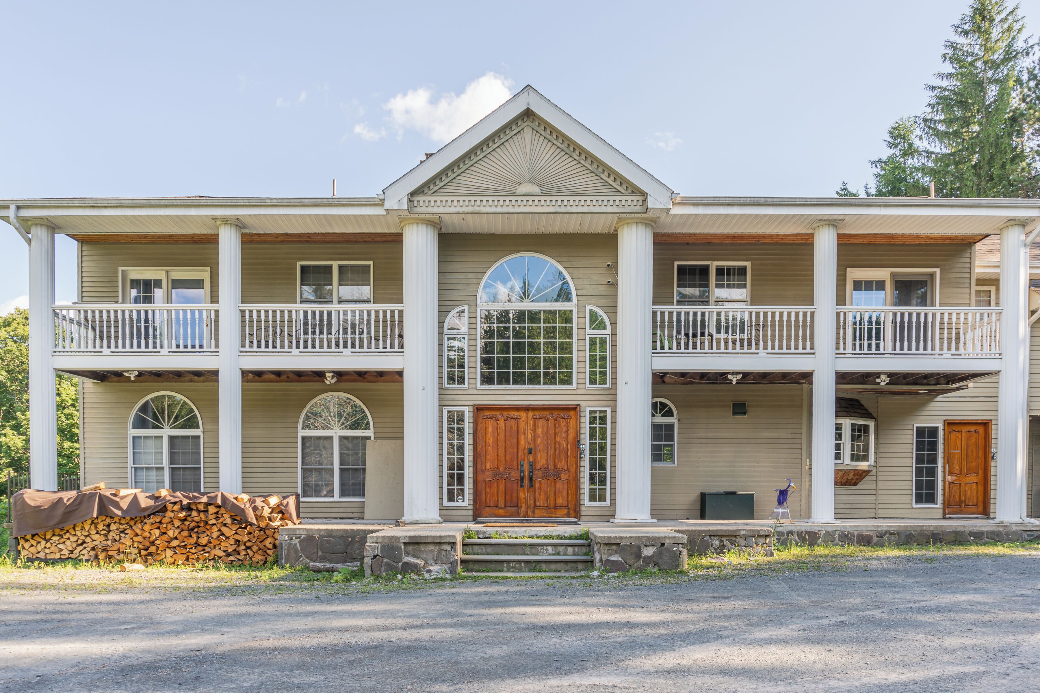 Grand columned estate with balconies and striking lodge-style entrance