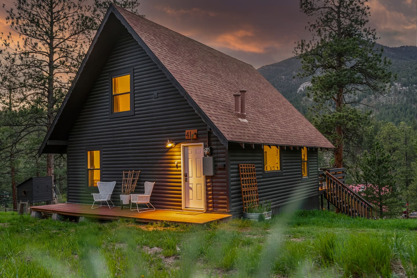 Front of the A-frame at dusk with warm light in the windows
