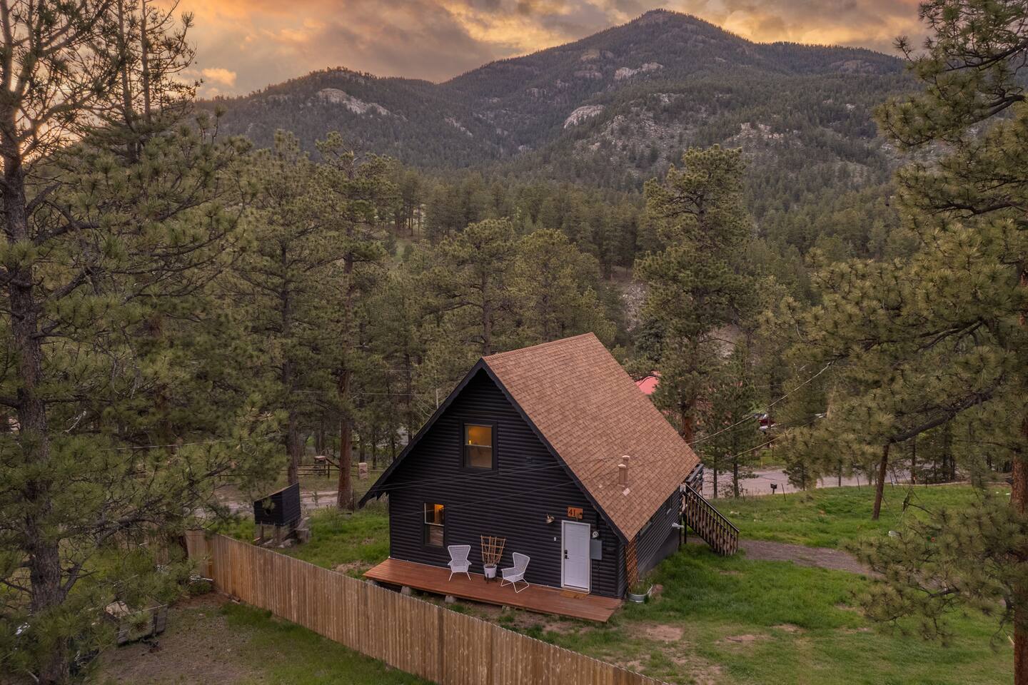 Aerial view of the A-frame among pines with the mountains behind