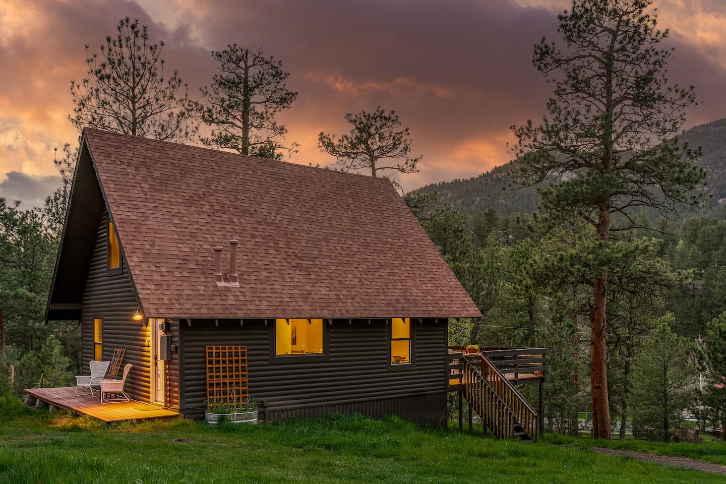 The Elegant A-Frame at sunset, windows glowing, with pines and a mountain behind it