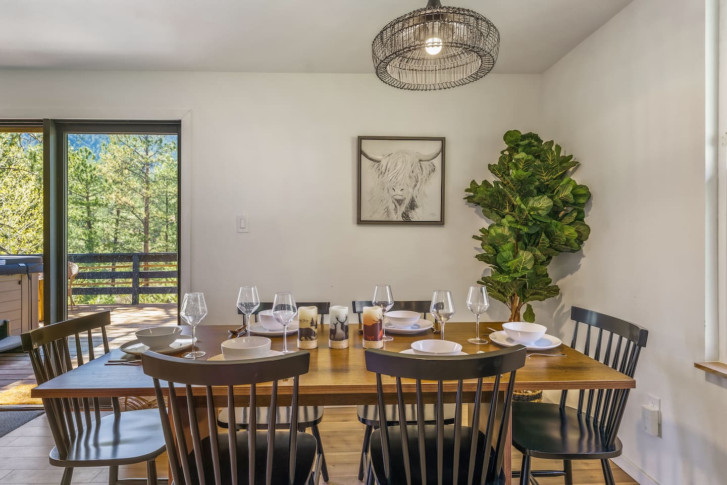 Dining table set for six next to a window onto the trees