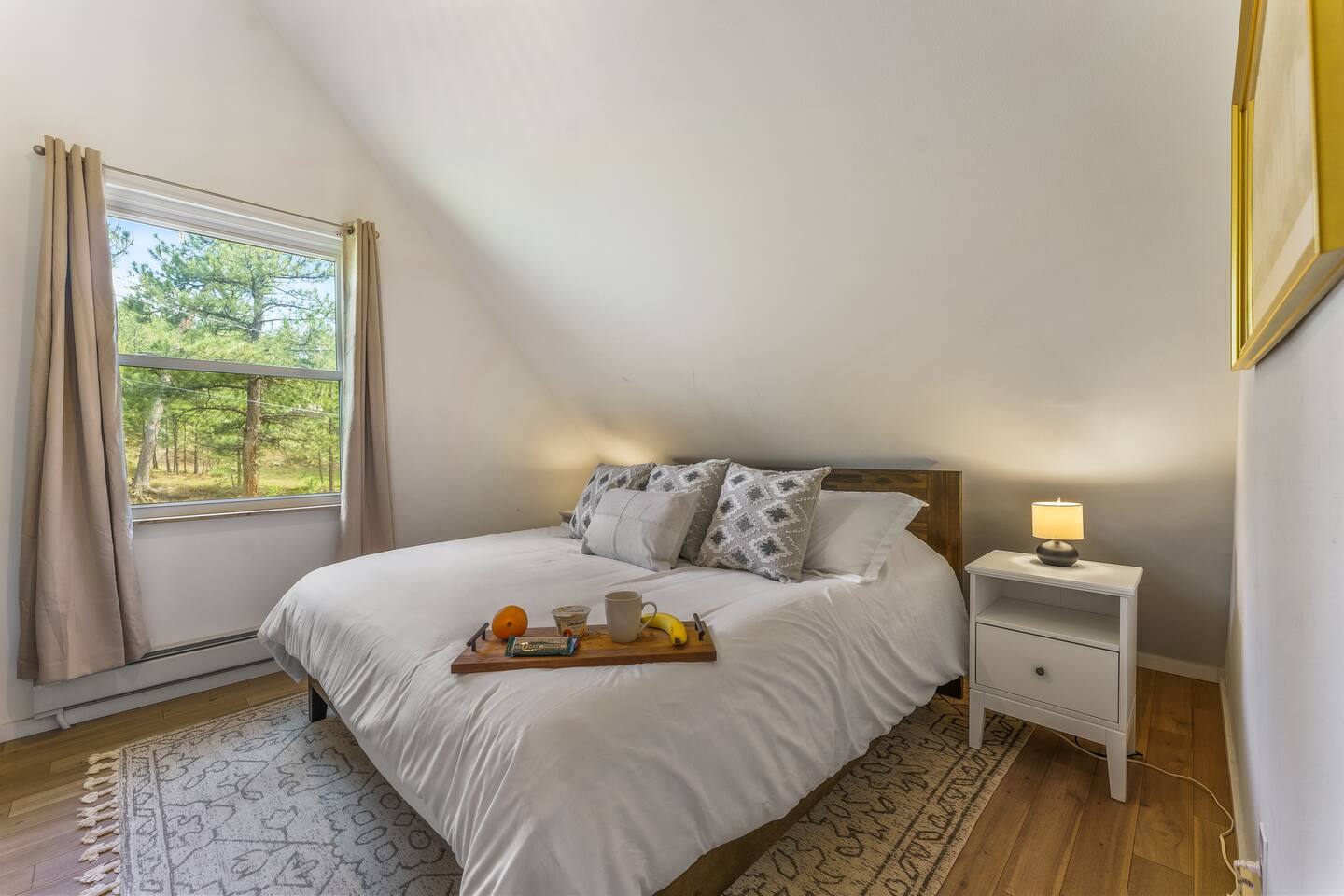 Queen bedroom with soft lamps and a window onto the pines