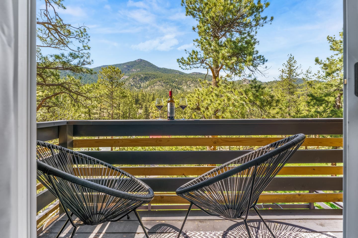 Private deck off the primary bedroom with two chairs and a mountain view