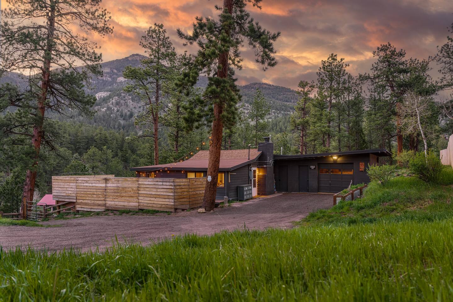 Cozy Cabin at sunset among tall pines, with the mountains behind it