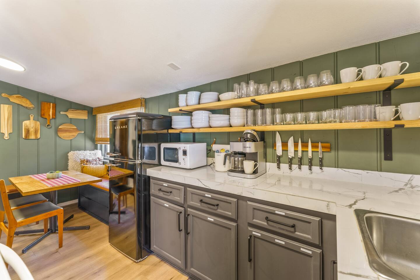 Kitchen with open shelves, white counters and a retro fridge