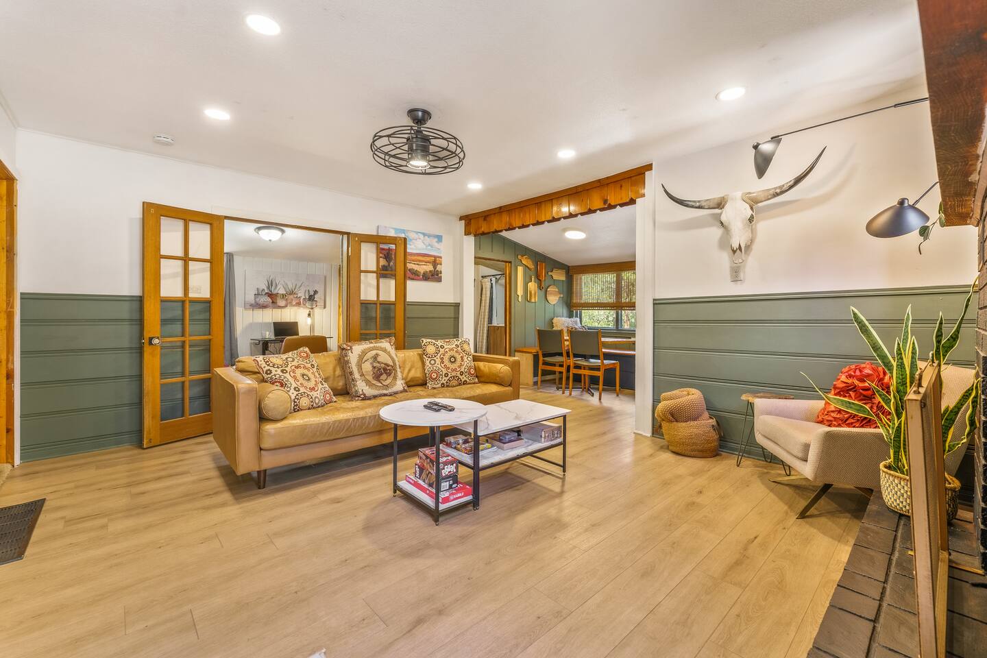 Living room with a leather sofa, green paneling and a longhorn skull over the doorway