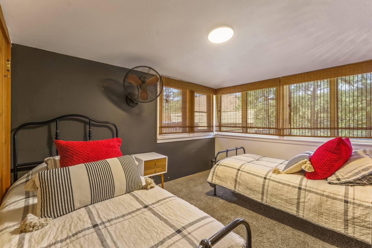 Twin bedroom with two beds, red pillows and a wall of windows