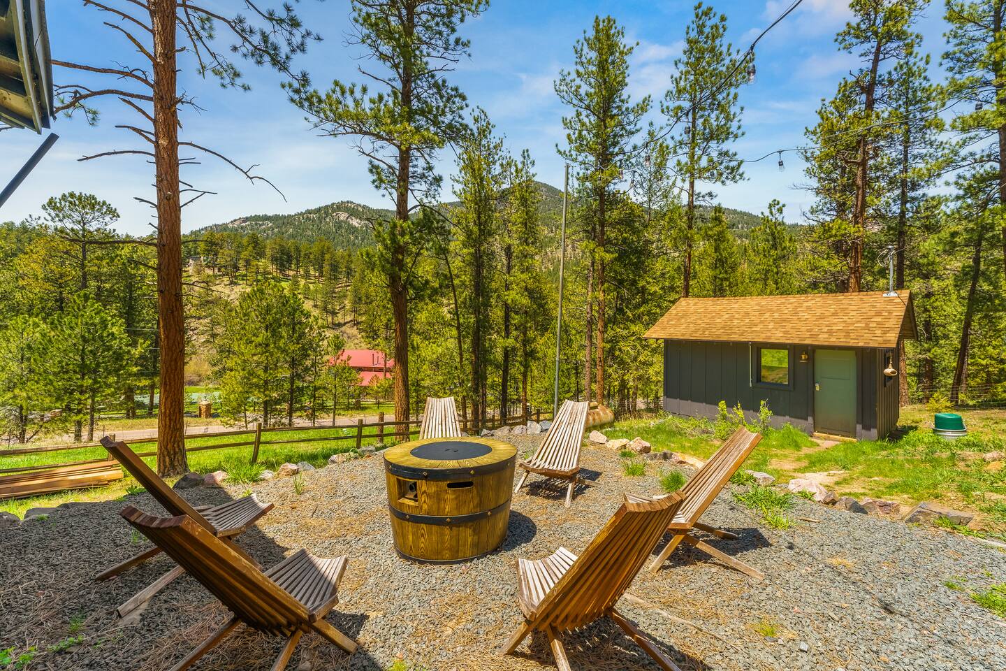 Fire pit circle in the yard with the Writer’s Nook and pines on a sunny day