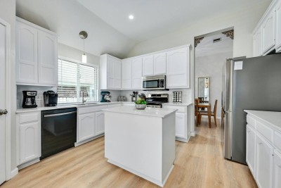 Fully Equipped White Kitchen! ‍️ This bright, modern kitchen features pristine white cabinetry and a central kitchen island. Includes stainless steel appliances. Plenty of counter space for meal prep and easy access to the dining area.