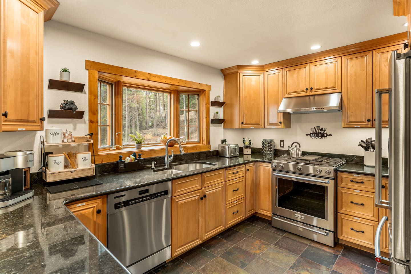 Kitchen with wood cabinets, stainless appliances and a window onto the trees