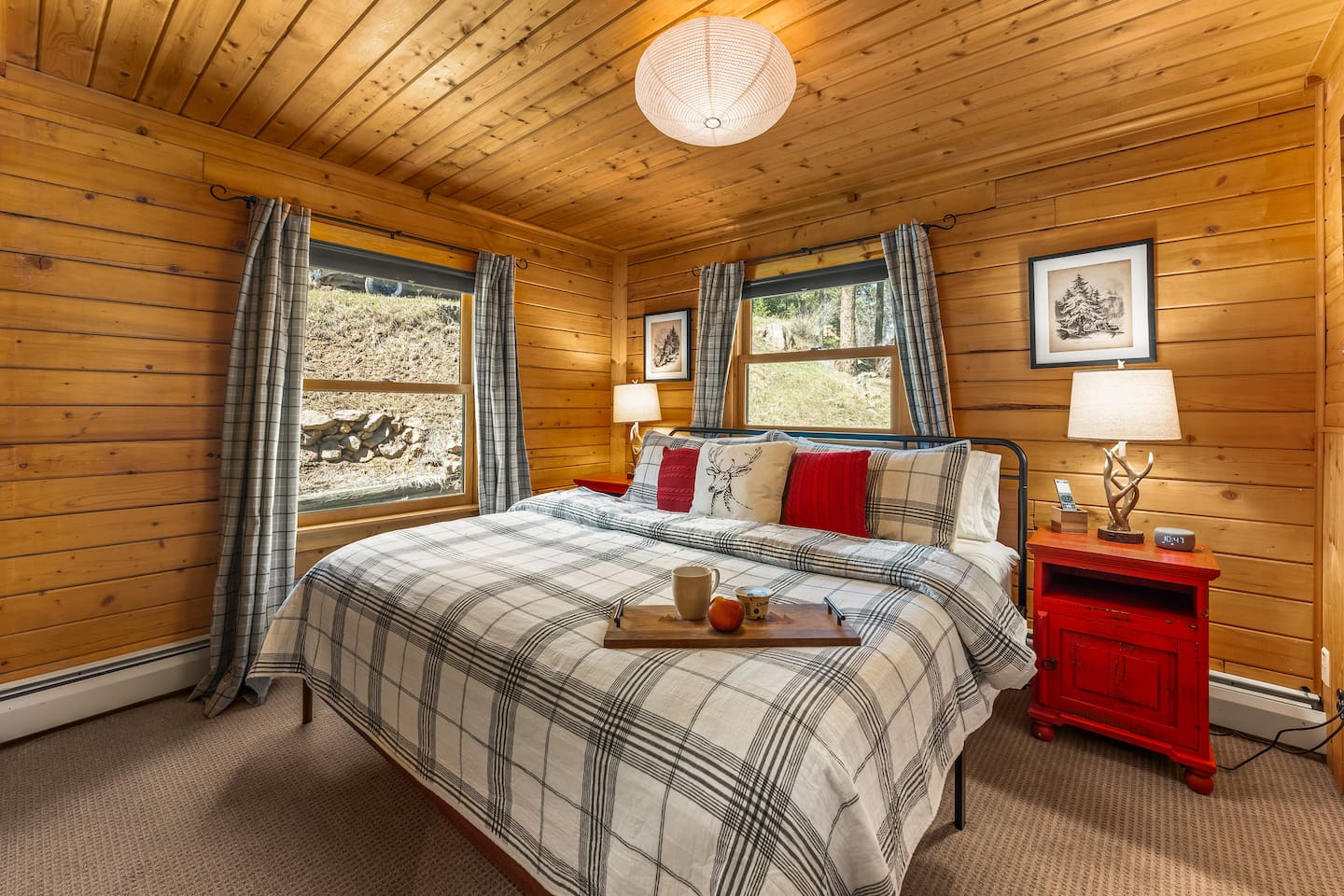 Main-floor king bedroom with plaid bedding and red pillows
