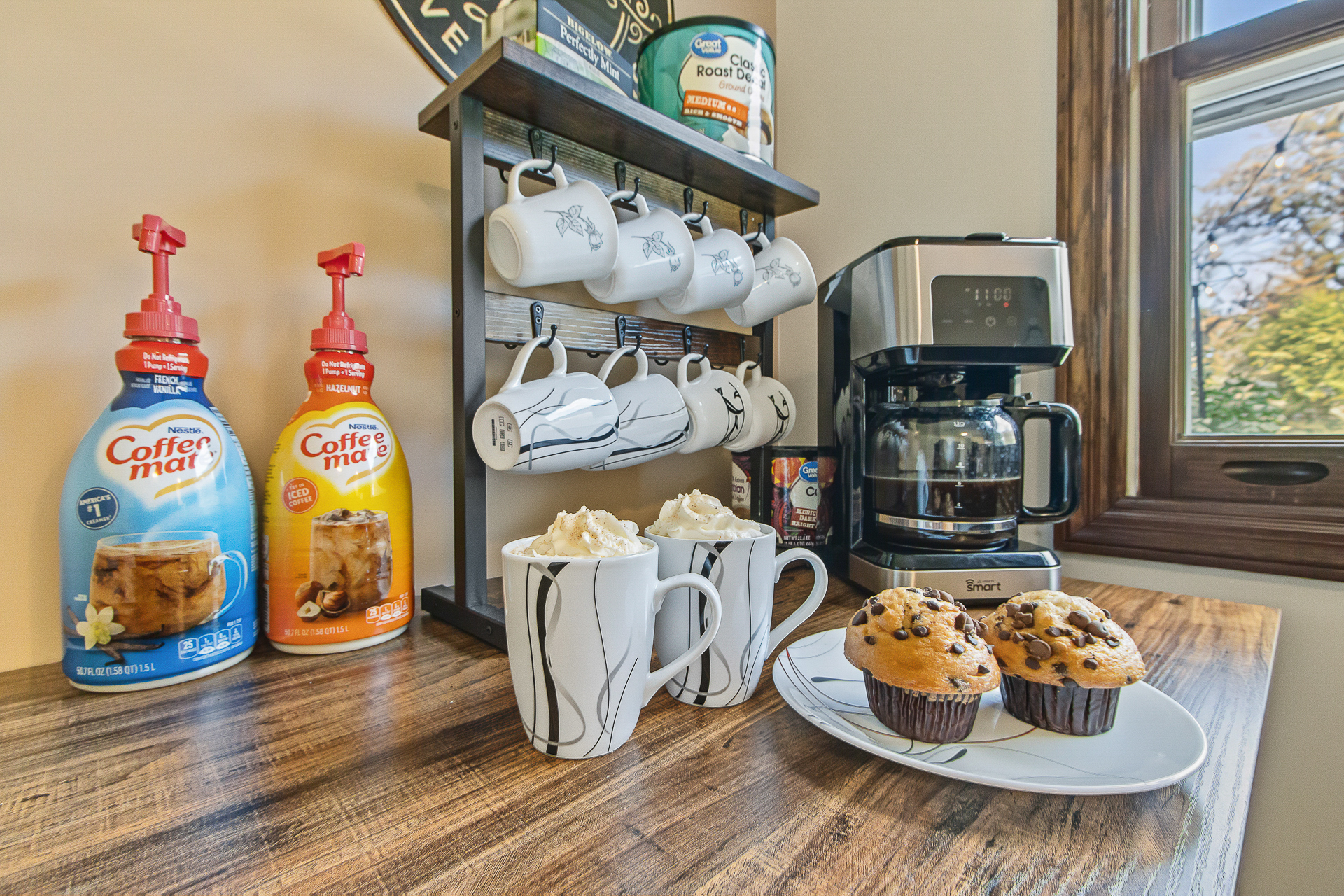 Cozy coffee bar with muffins, creamers, and window-side natural light
