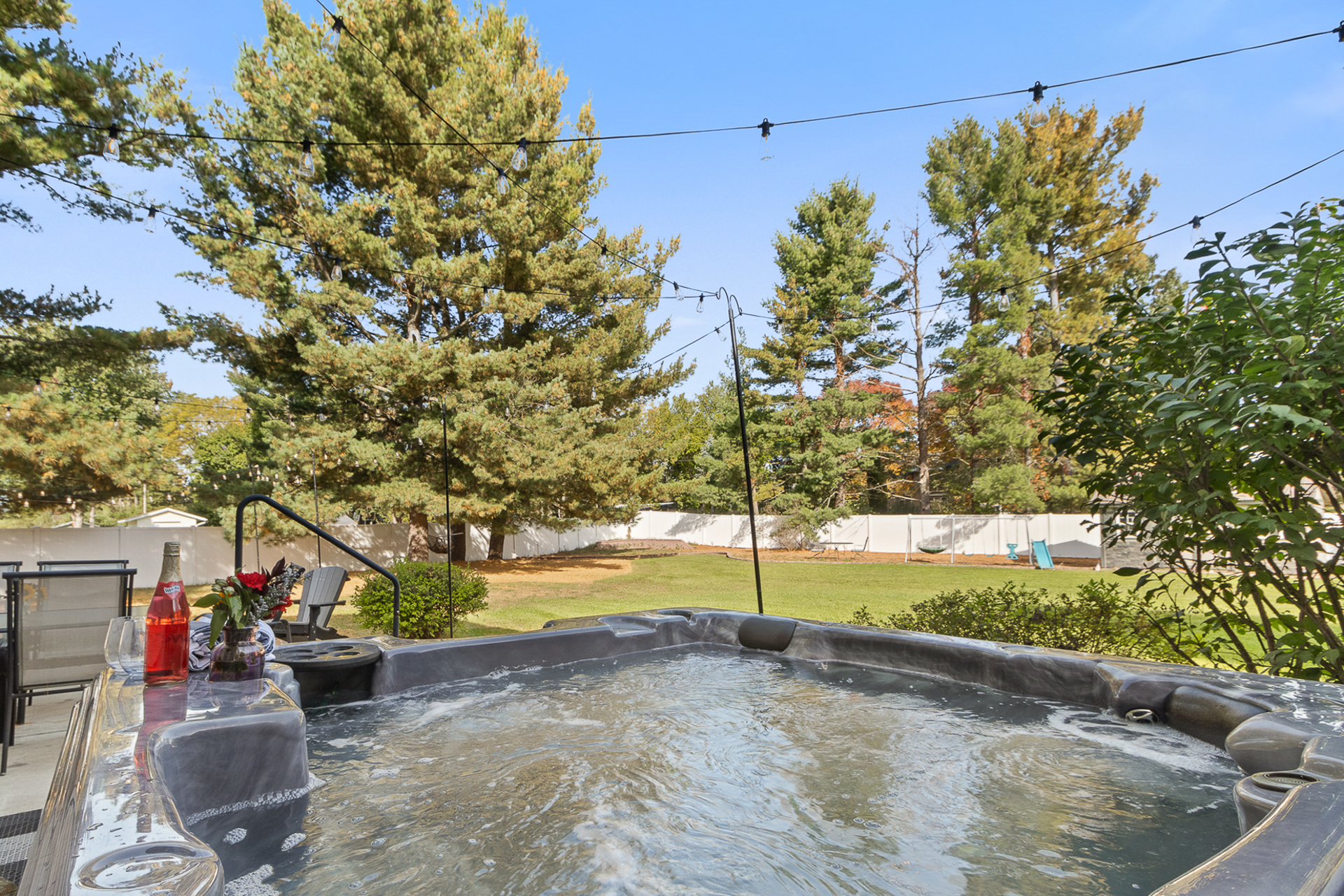 Private backyard hot tub with string lights and a spacious lawn