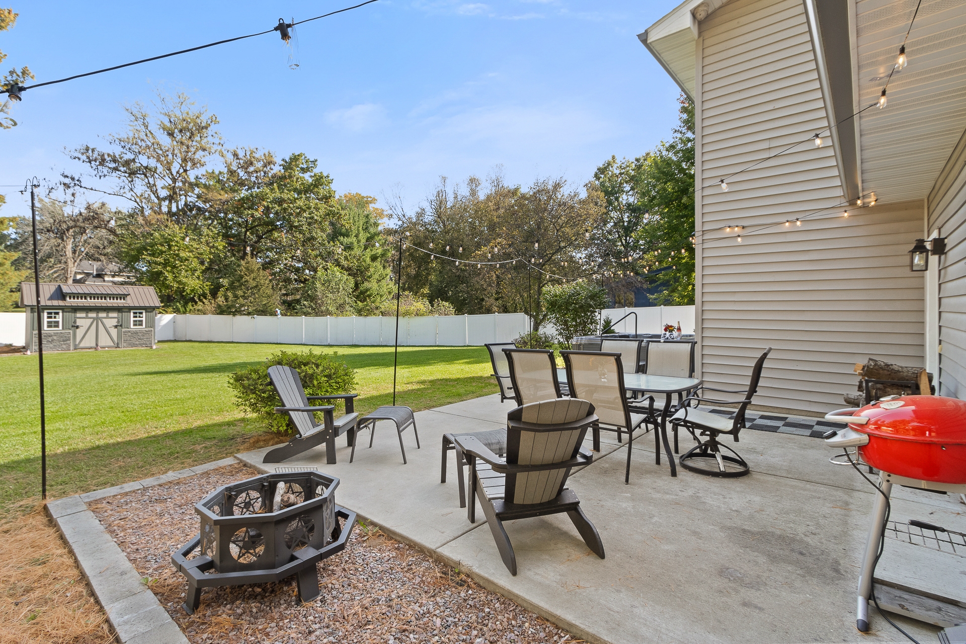 Spacious fenced backyard patio with fire pit, grill, and outdoor dining