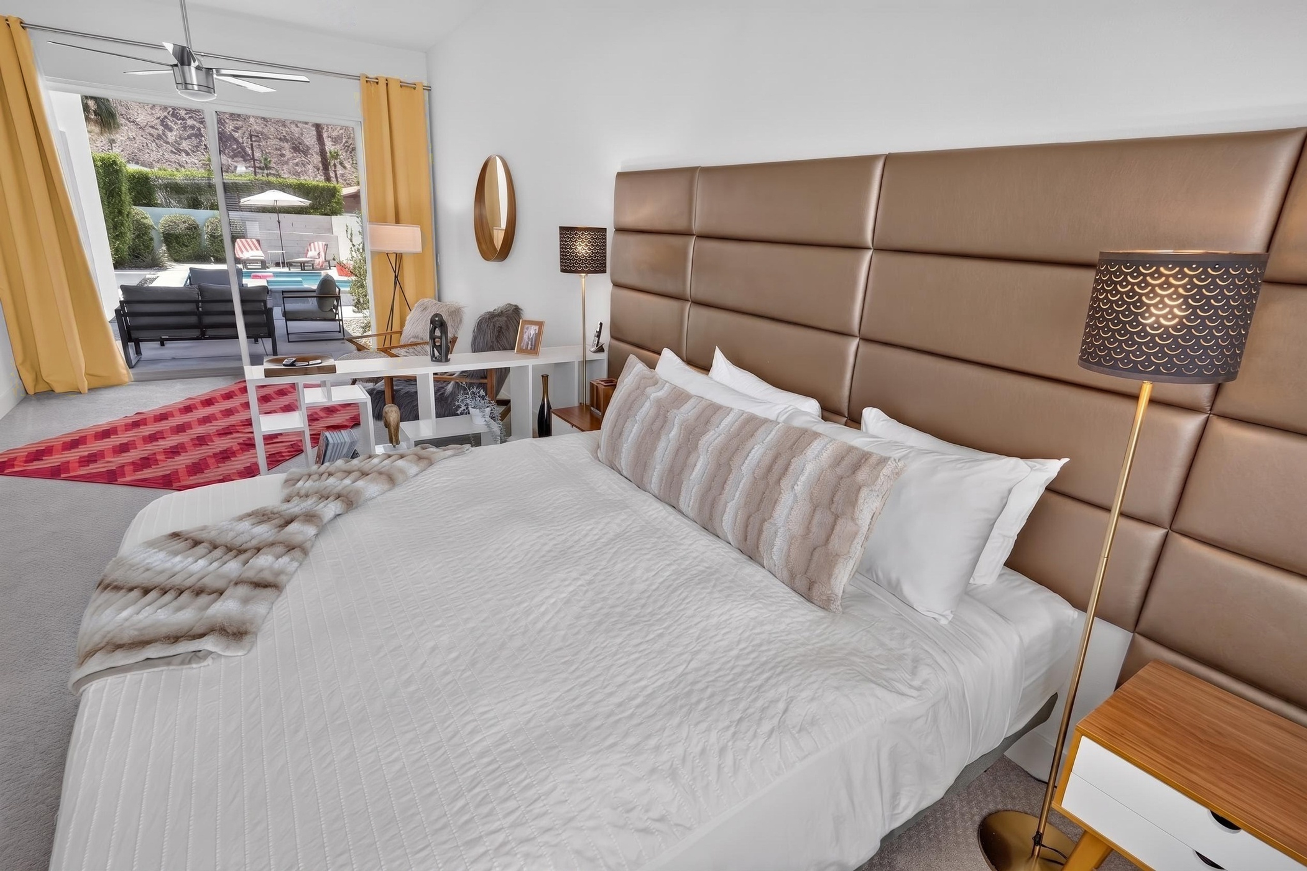 Bright king bedroom with patio access, workspace, and poolside views