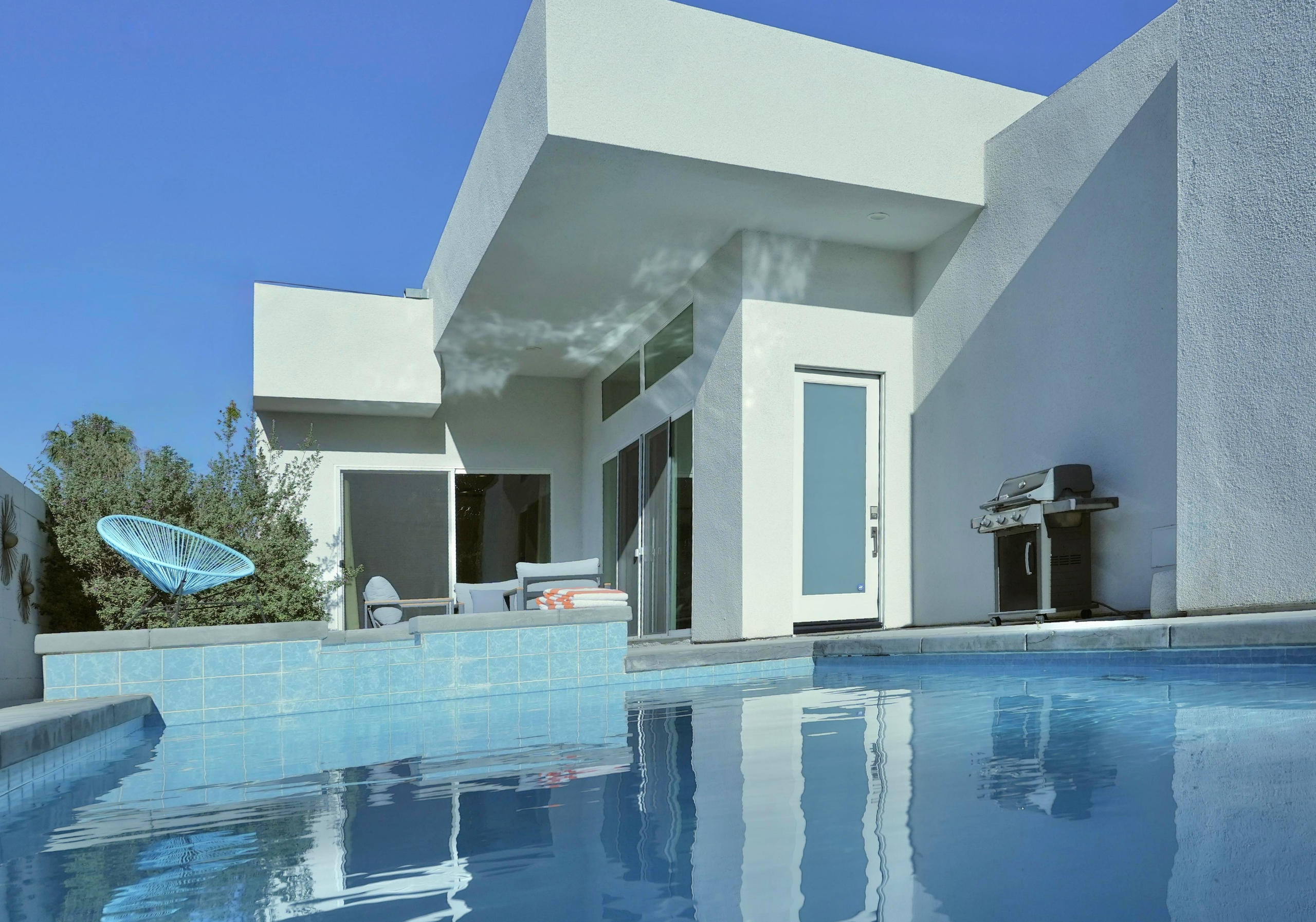 Private pool patio with modern design, grill, and sunny lounge space