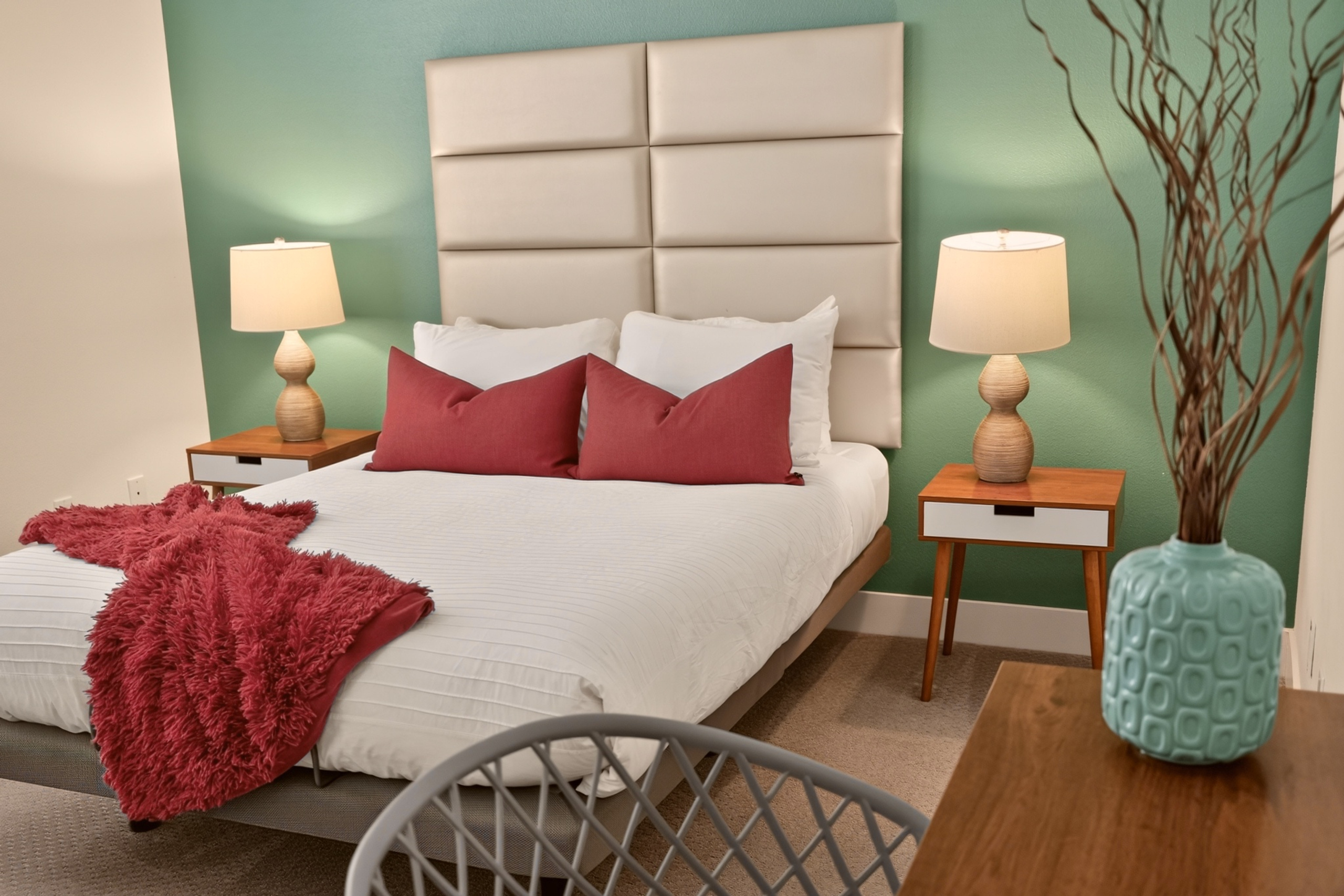 Stylish, cozy bedroom with plush bedding and a modern teal accent wall