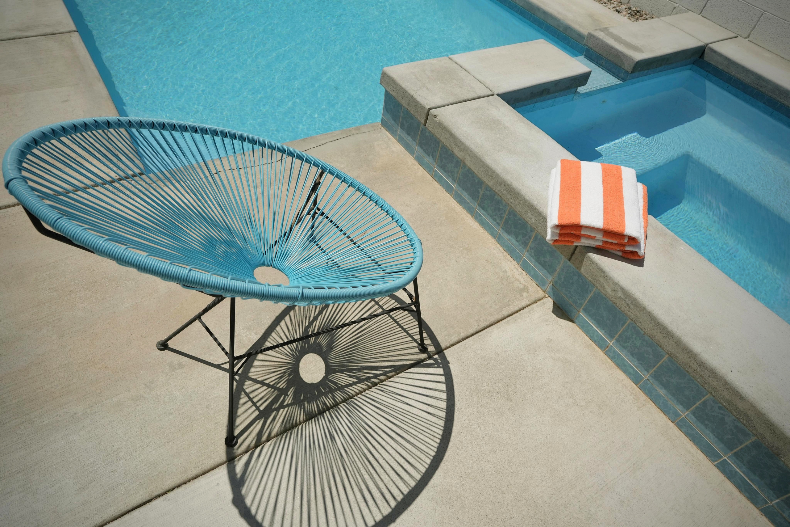 Sunny poolside lounge with sparkling pool, spa, and stylish seating