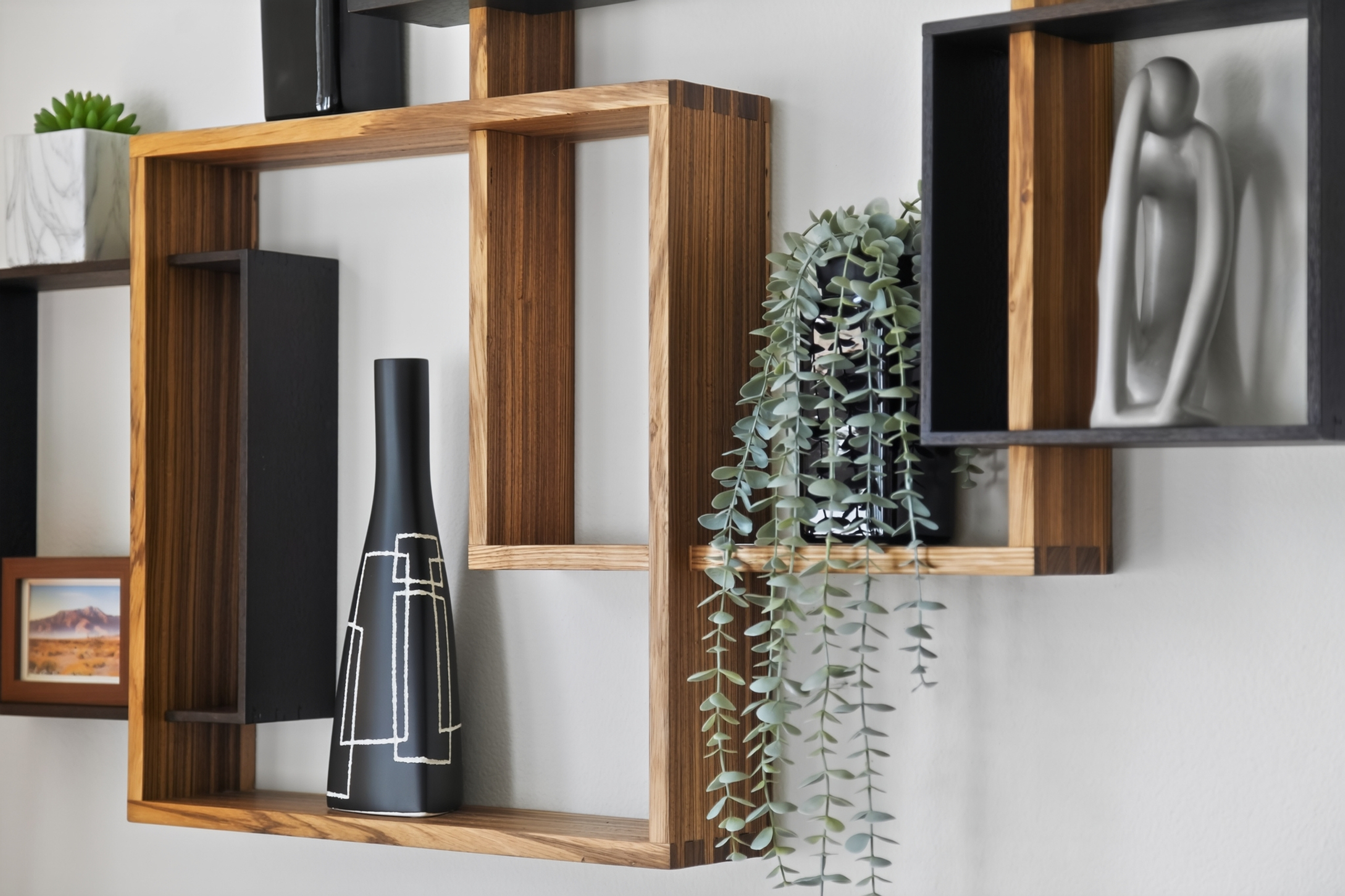 Modern wood wall shelves with curated decor and lush greenery accents
