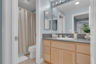 Bright Guest Full Bathroom!  This clean, well-lit bathroom features a tub/shower combination with a stylish striped curtain. Enjoy the spacious vanity with ample storage, large mirror, and bright lighting.