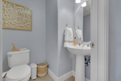 Stylish Half Bathroom! ️ This sophisticated powder room features a sleek pedestal sink and a large, modern round mirror. Calming blue-gray walls and designer art create a luxurious feel. Clean, bright, and conveniently located for common areas. 