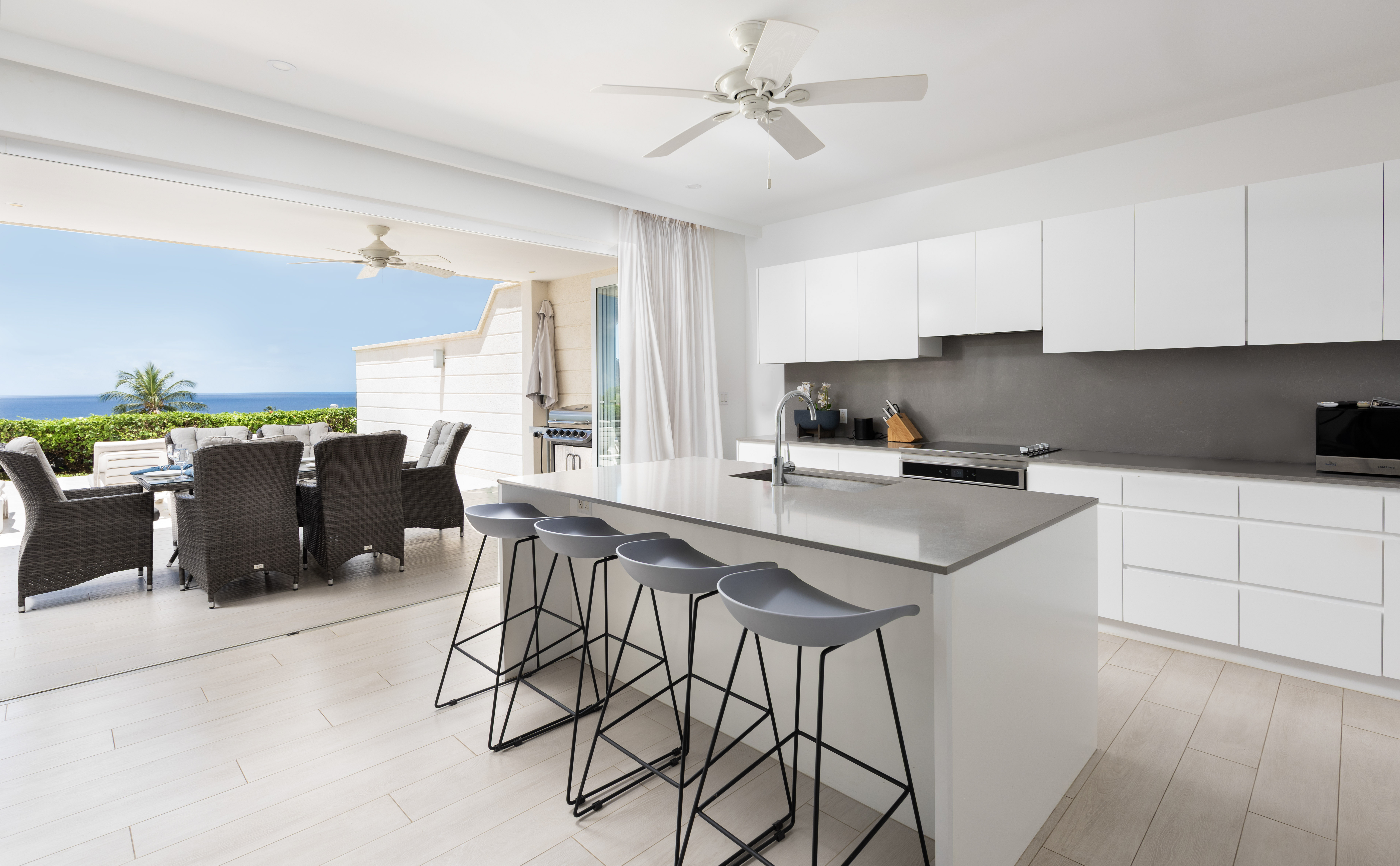 Modern ocean-view kitchen with island seating and alfresco dining