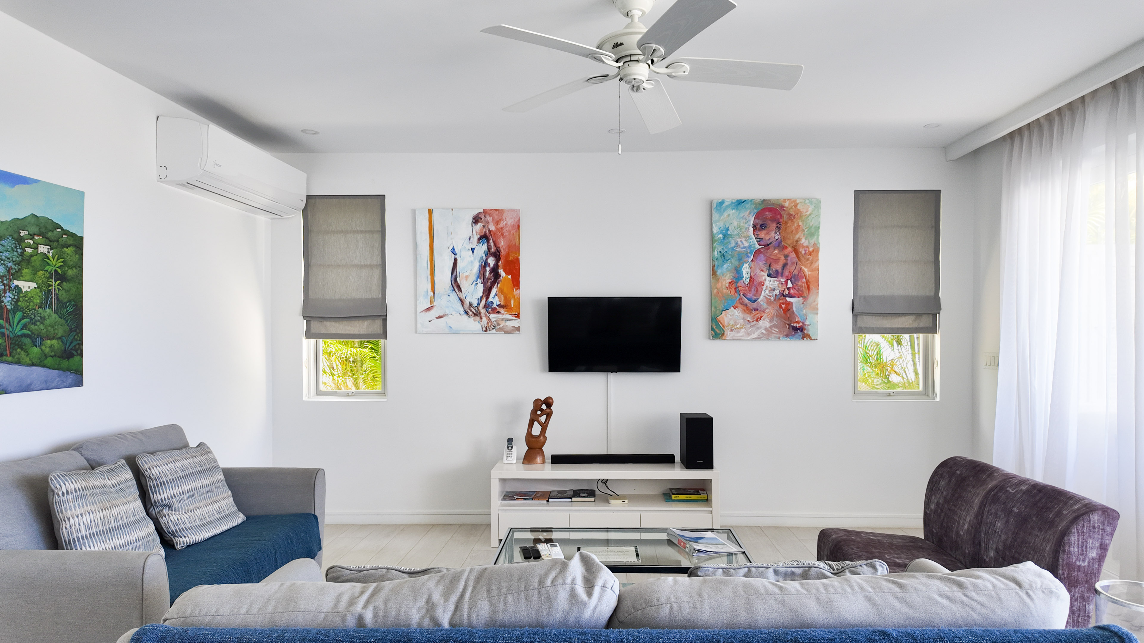 Bright modern lounge with wall-mounted TV, art, and abundant natural light