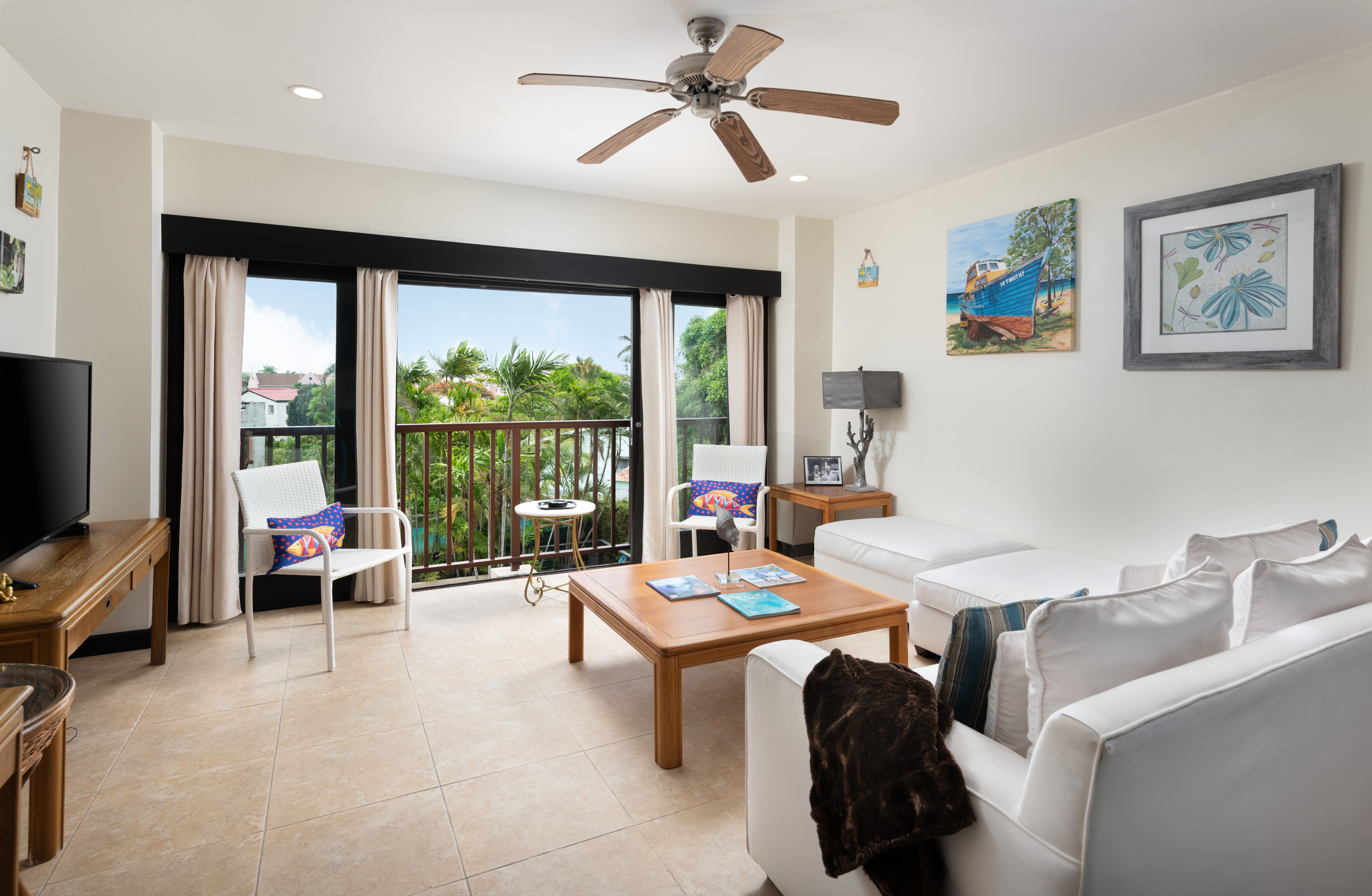 Bright tropical living room with private balcony and lush garden views