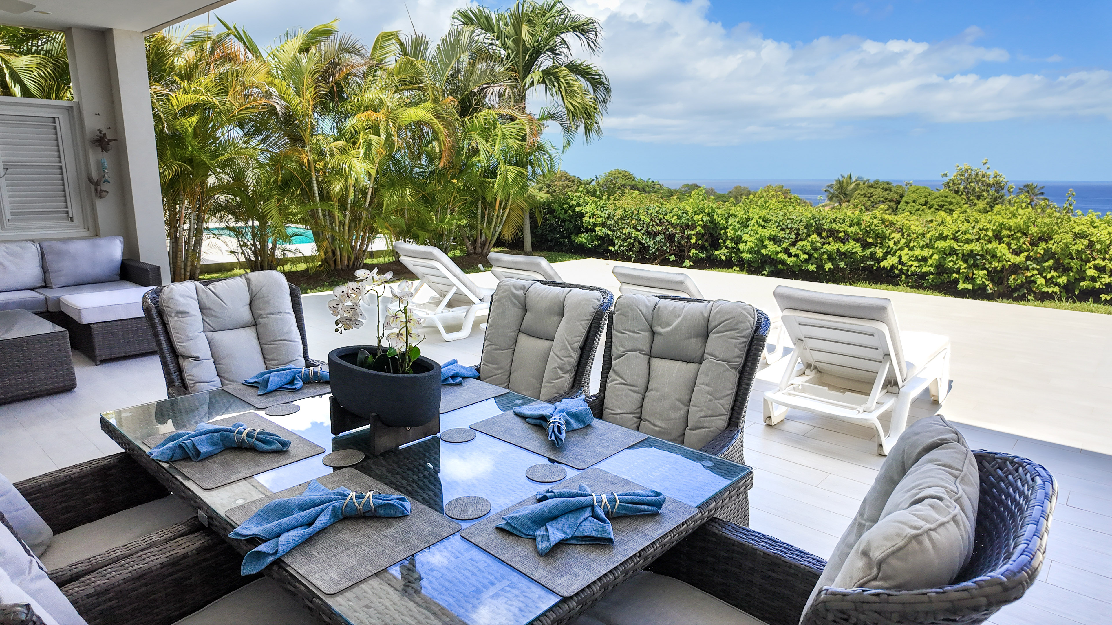 Covered ocean-view patio with tropical loungers and stylish outdoor dining