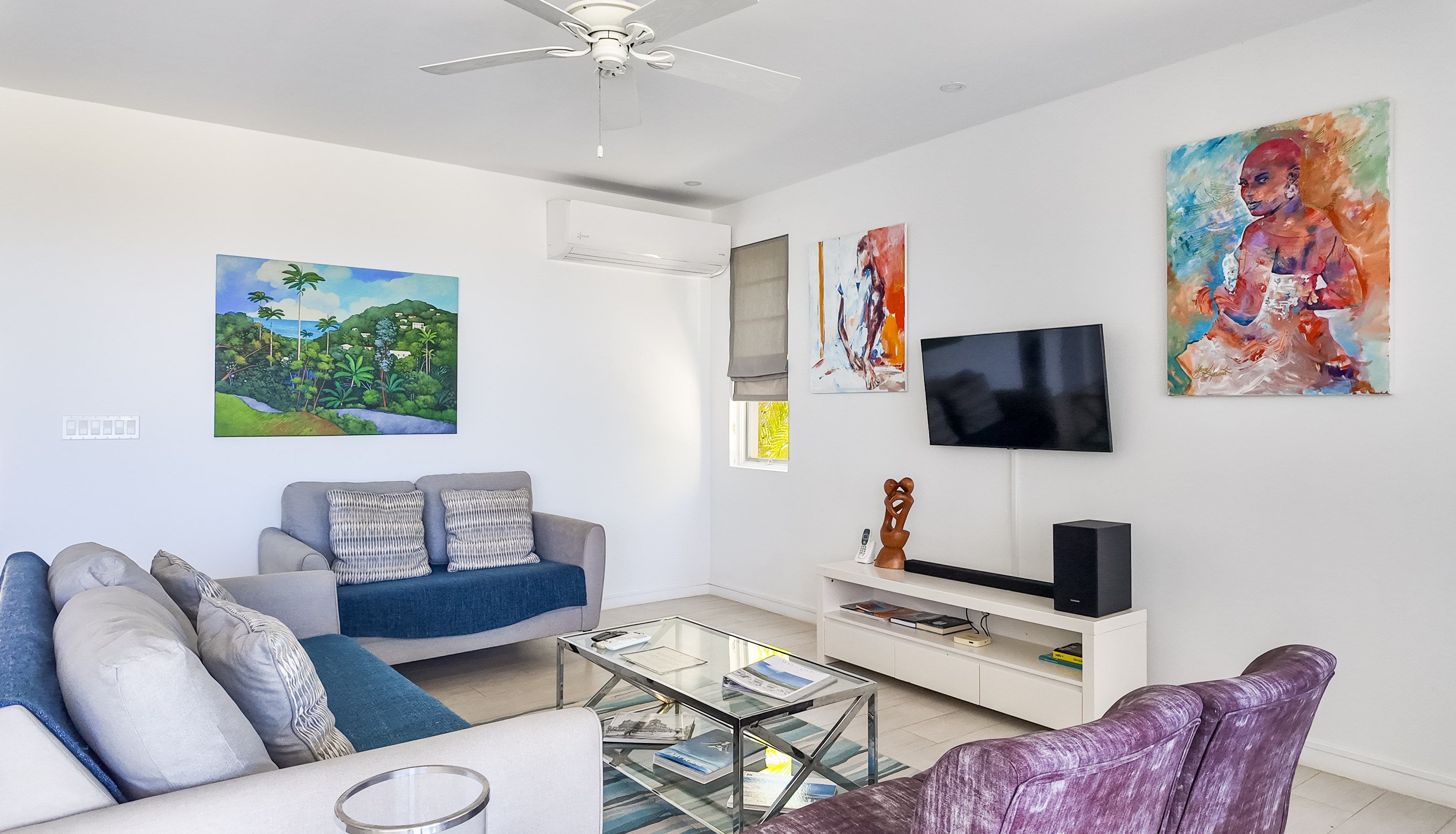 Bright modern lounge with AC, smart TV, and colorful local artwork