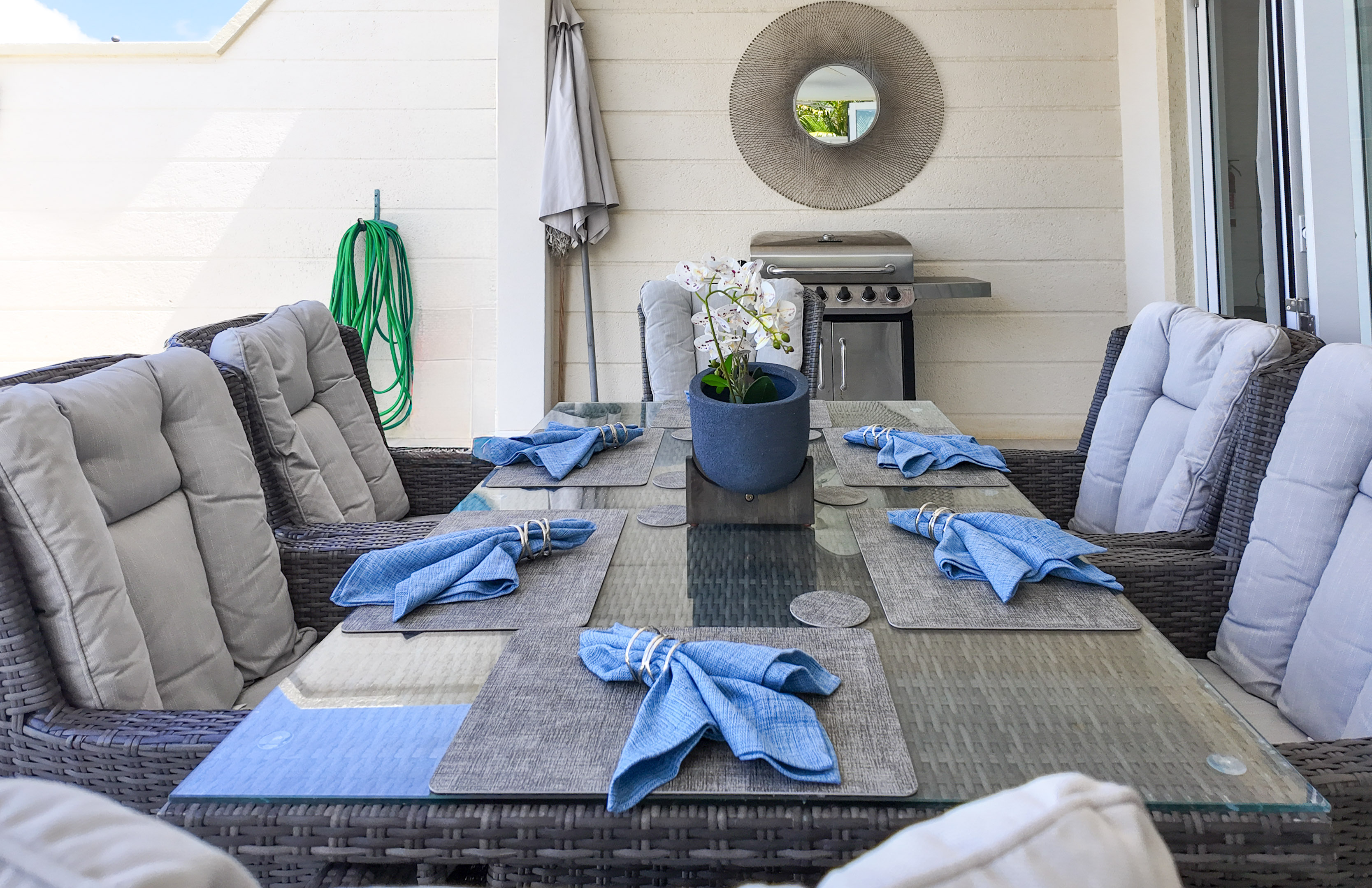 Stylish covered patio dining with cushioned seating and BBQ grill