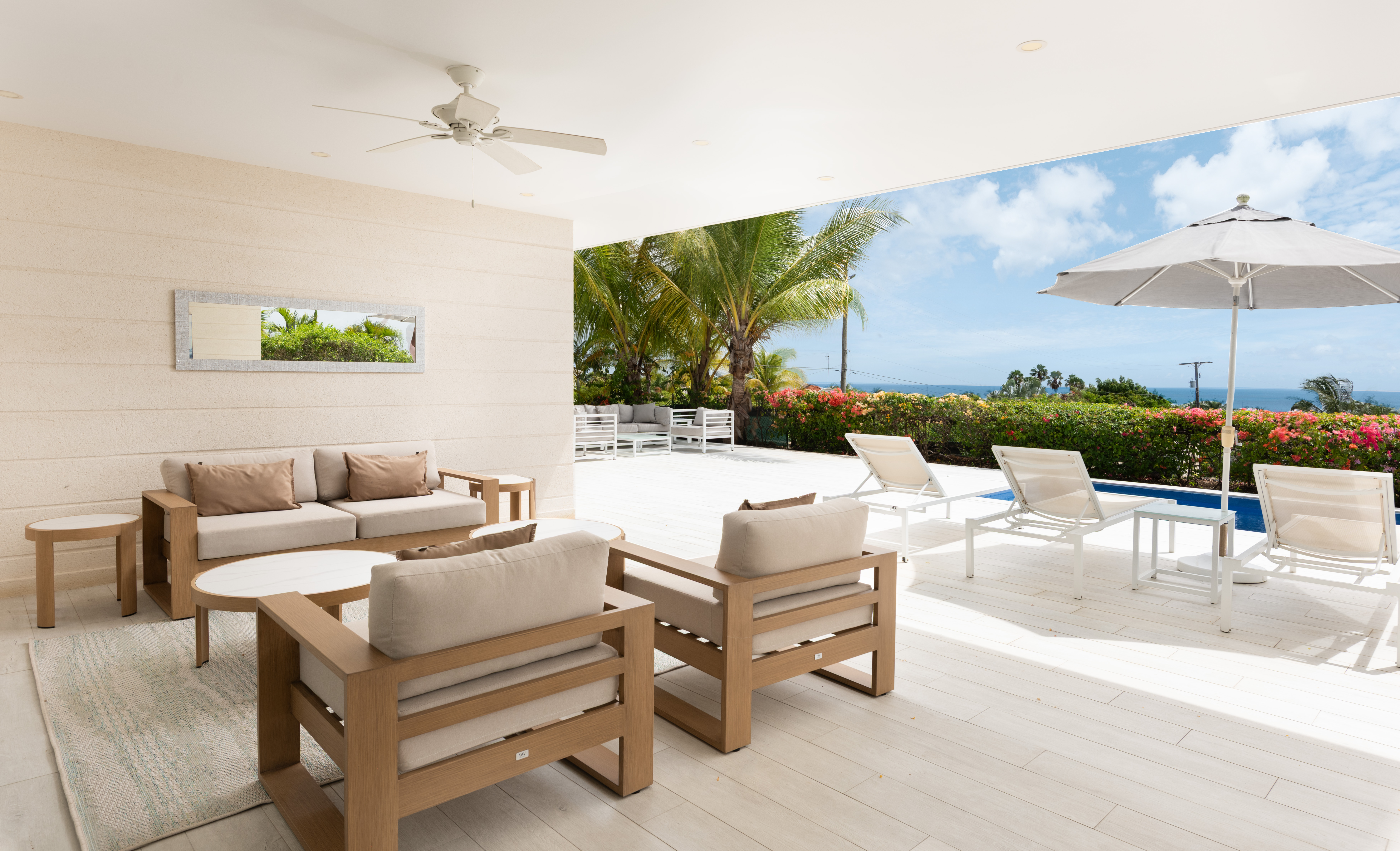 Bright covered lanai with poolside loungers and ocean views