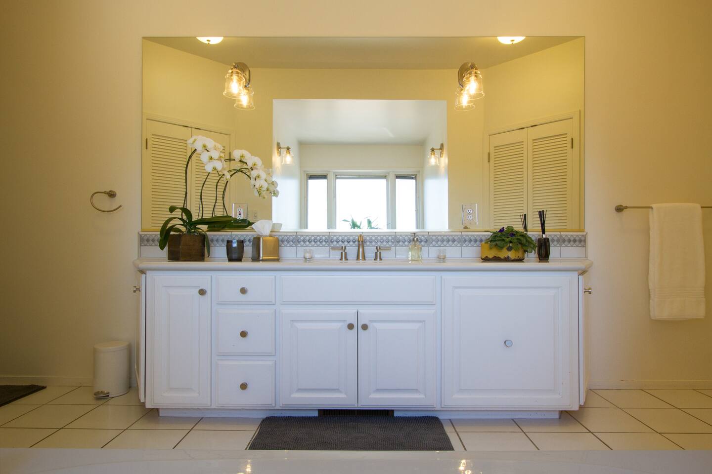 Get ready in style at the primary bath vanity, featuring a large mirror and abundant natural light. The bright, airy space adds a touch of luxury to your daily routine, making every moment feel effortlessly elegant.