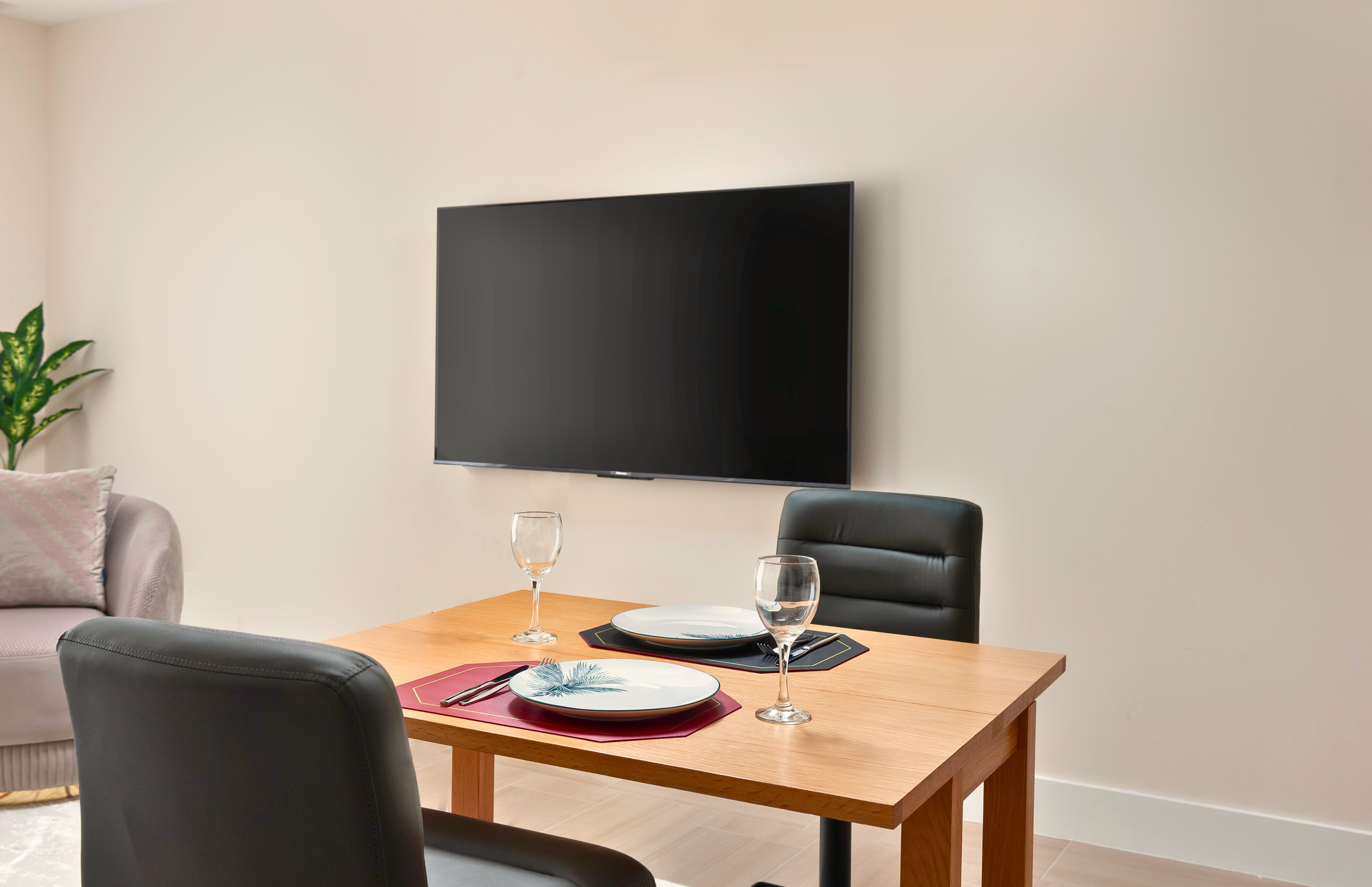 Cozy dining nook for two with a large wall-mounted TV