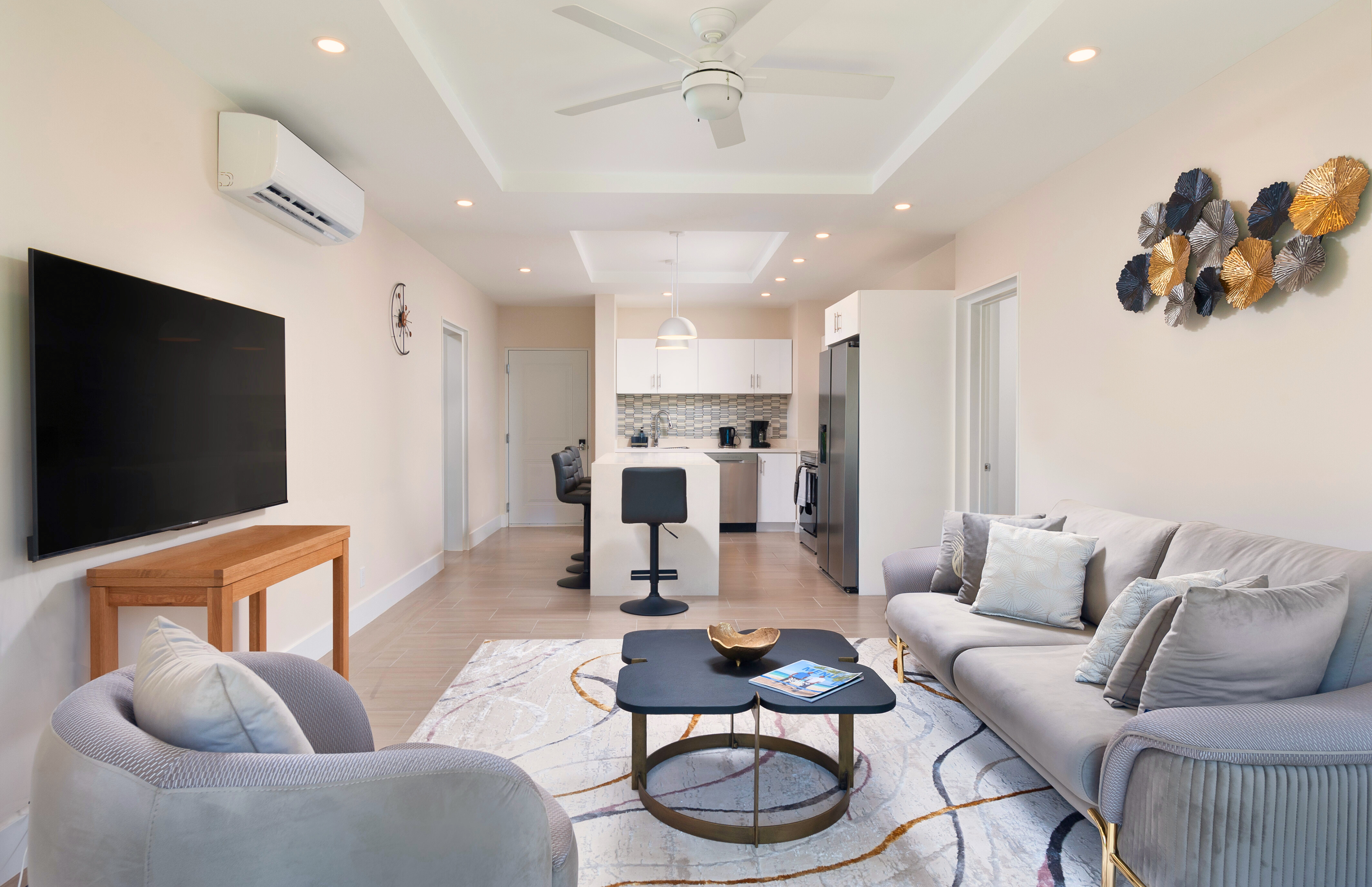 Bright modern lounge with TV, stylish seating, and open kitchen