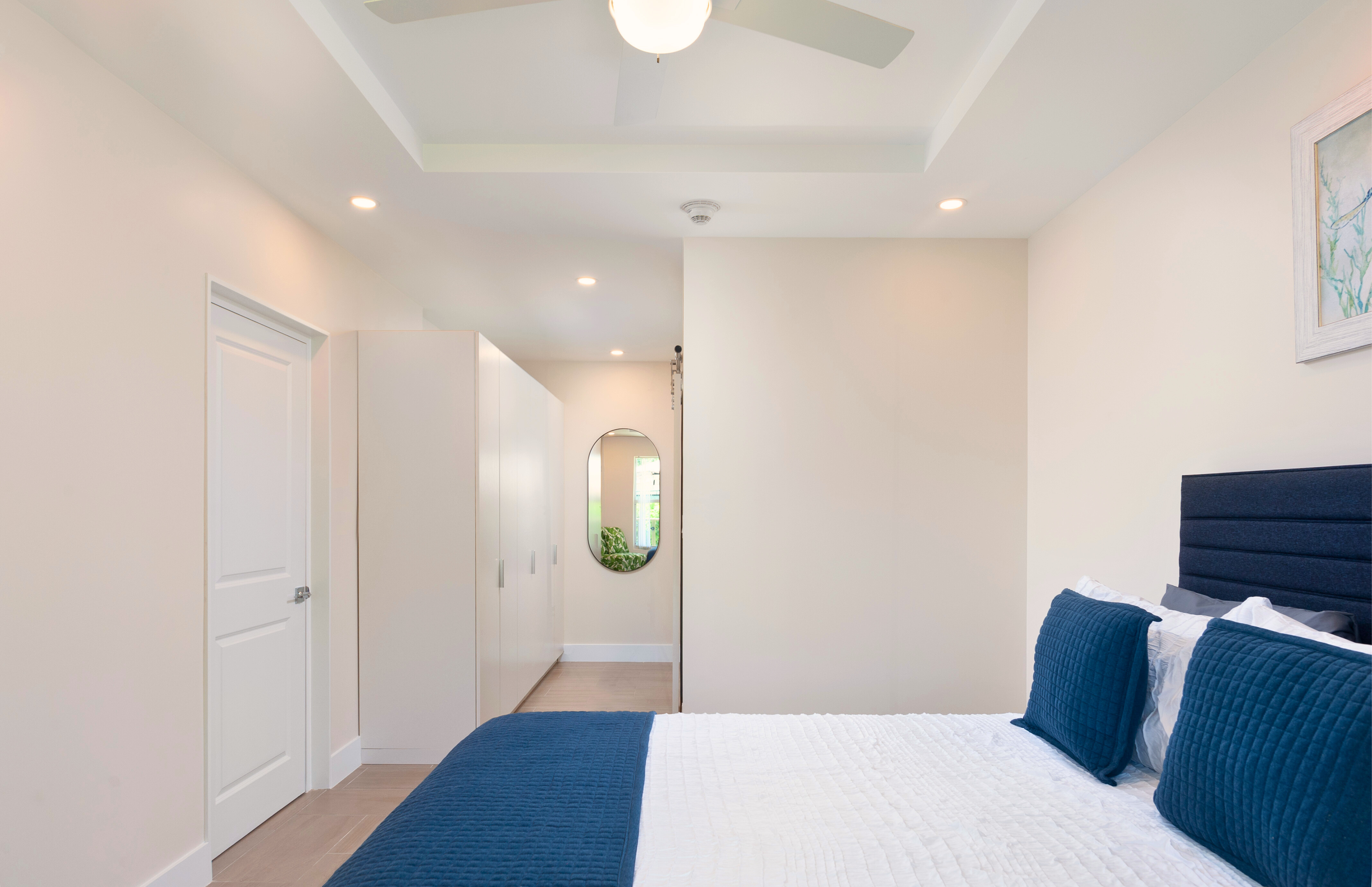 Bright modern bedroom with tray ceiling, closet space, and cozy blue accents