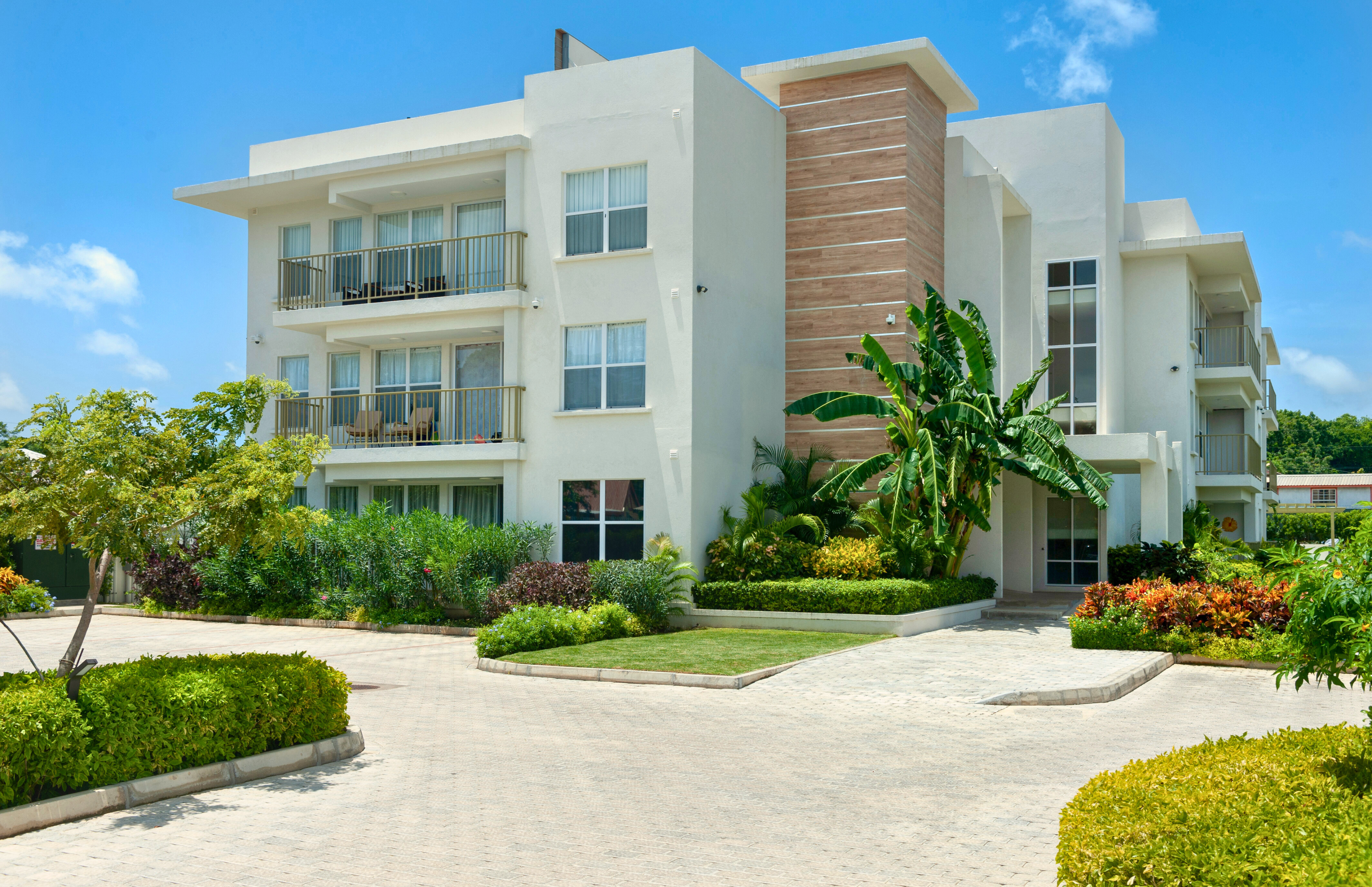 Modern tropical condo with balconies, lush gardens, and inviting curb appeal