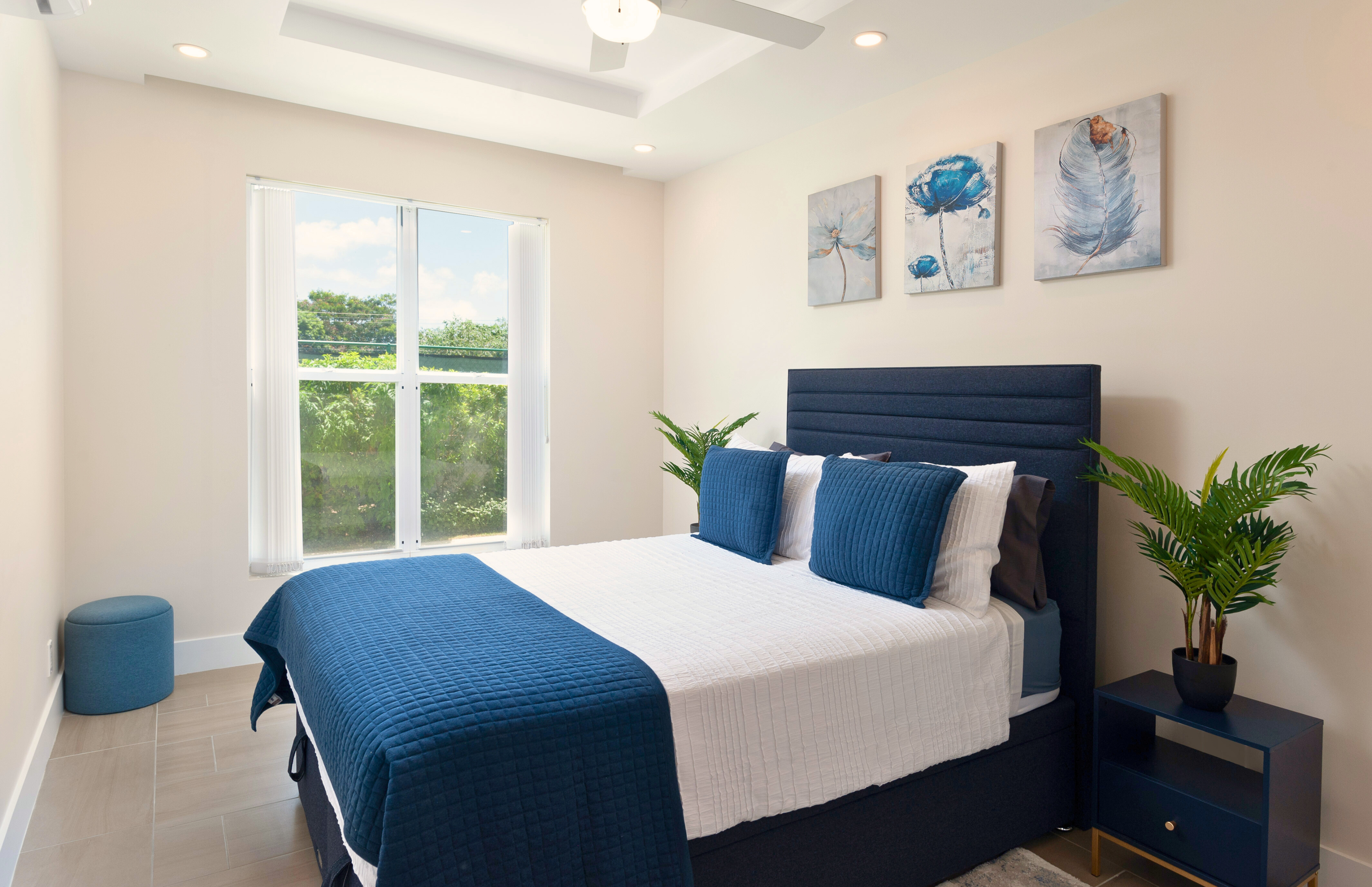 Bright modern bedroom with blue accents and peaceful garden views