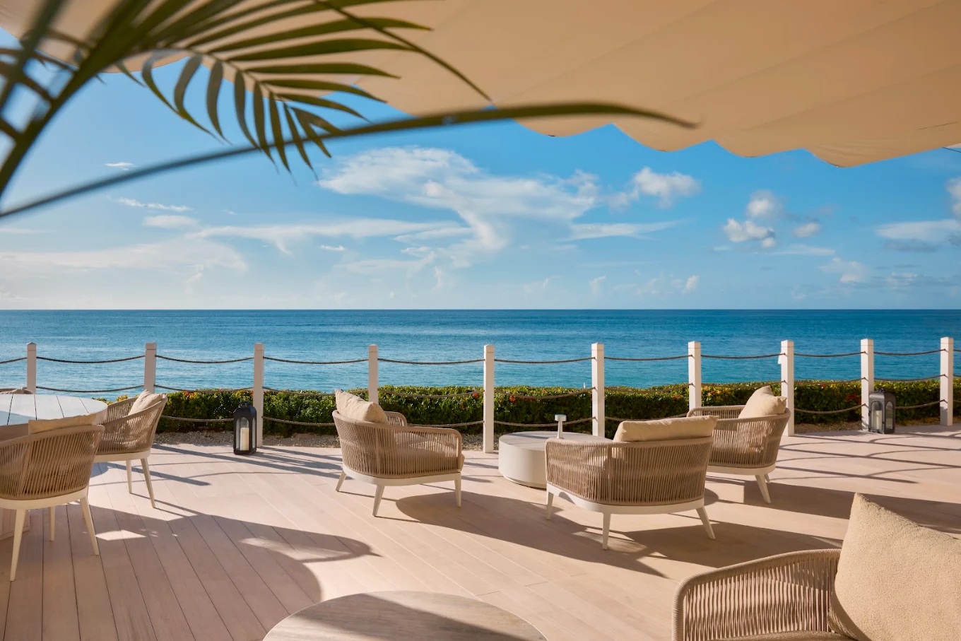 Elegant oceanfront terrace with shaded lounge seating and panoramic sea views