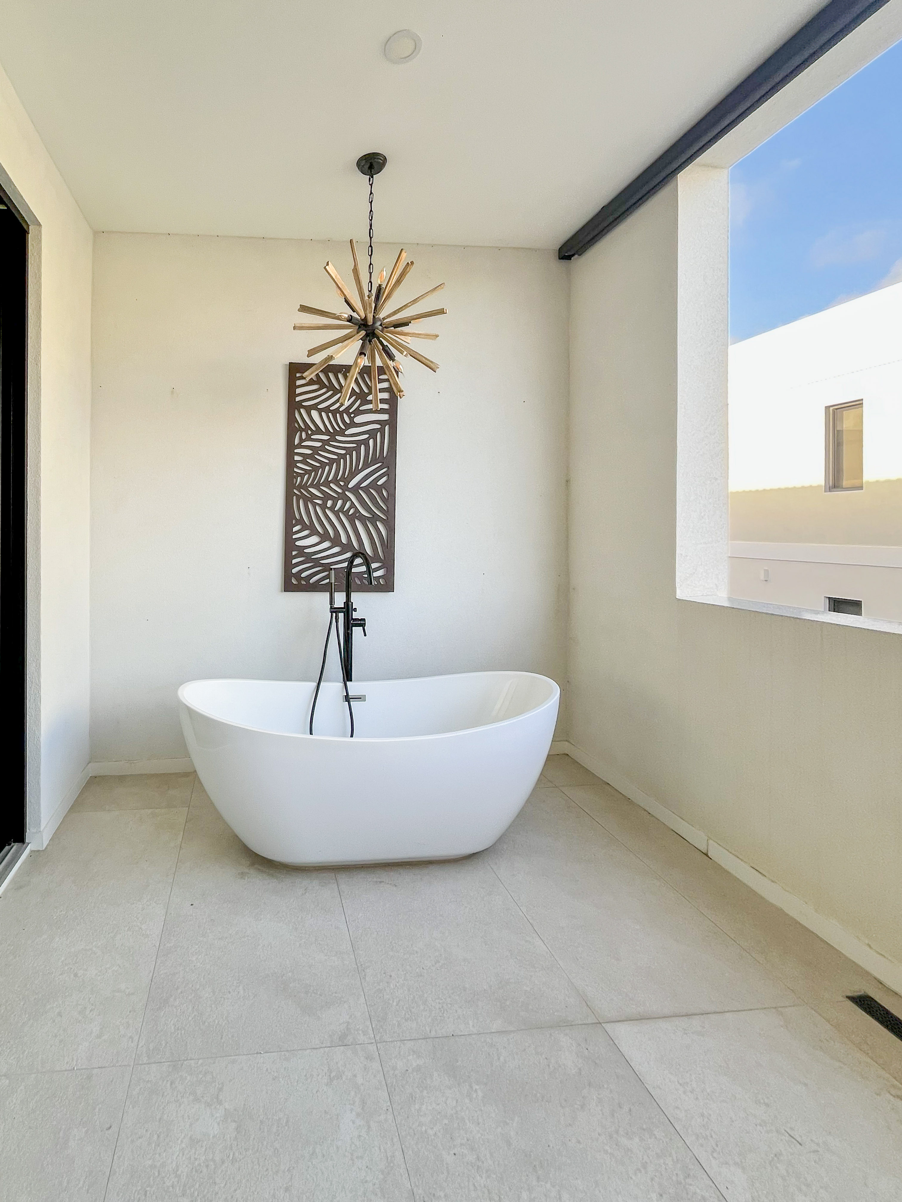 Spa-like soaking tub with chic chandelier and airy indoor-outdoor feel