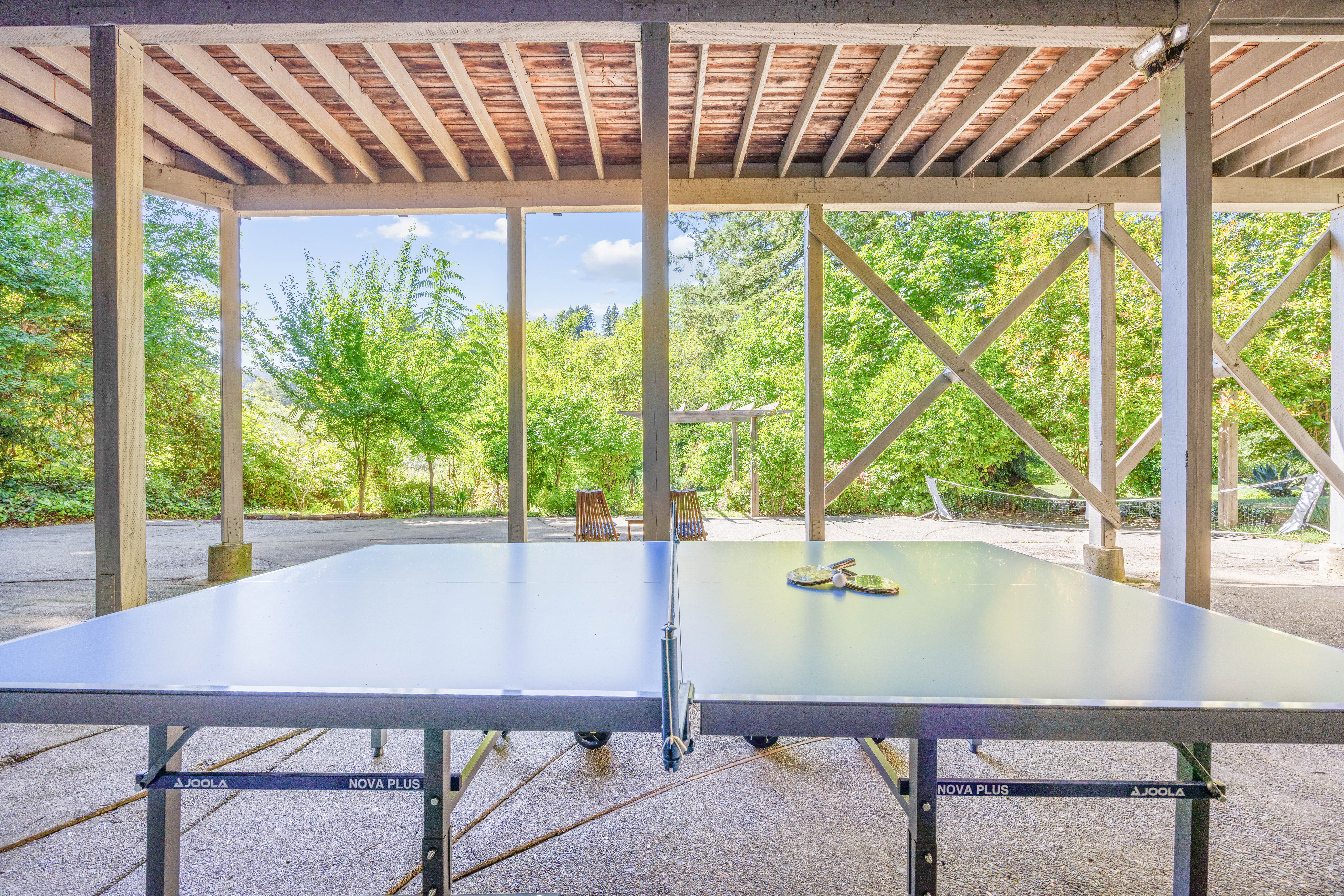 Covered outdoor ping pong area surrounded by peaceful greenery