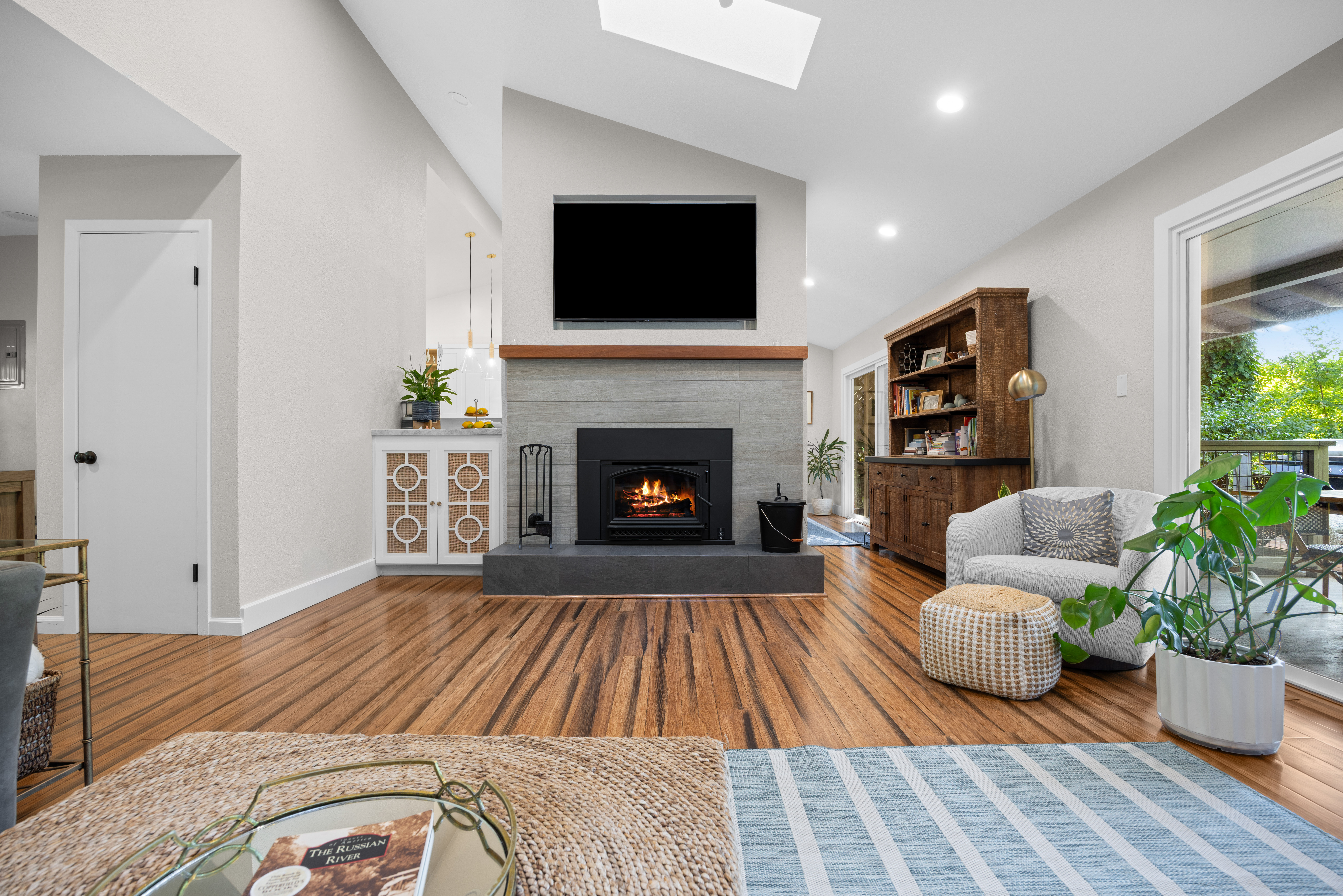 Bright vaulted living room with fireplace, TV, and cozy modern styling