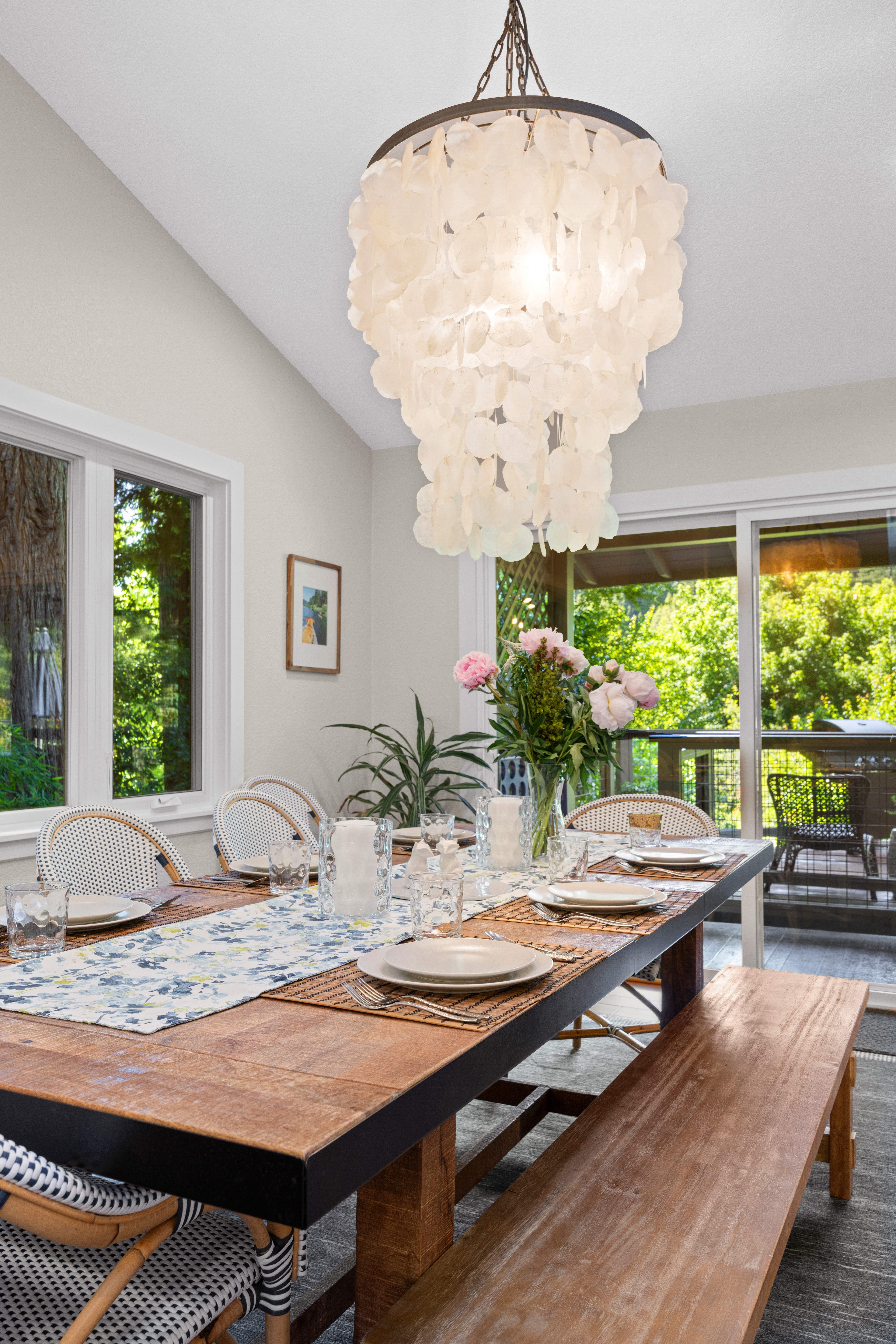 Bright dining space with statement chandelier and serene deck views