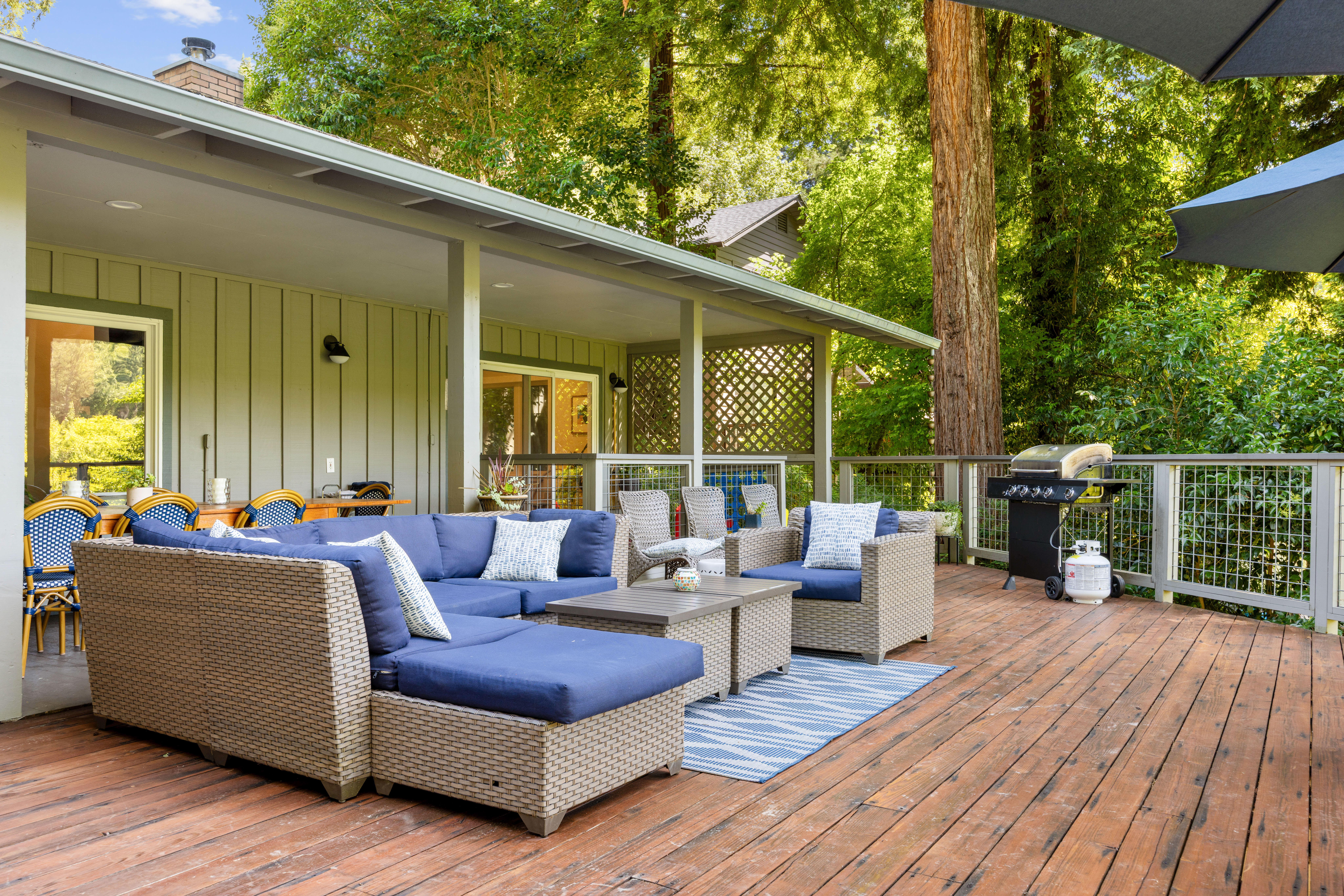 Private forest-view deck with lounge seating, dining area, and grill
