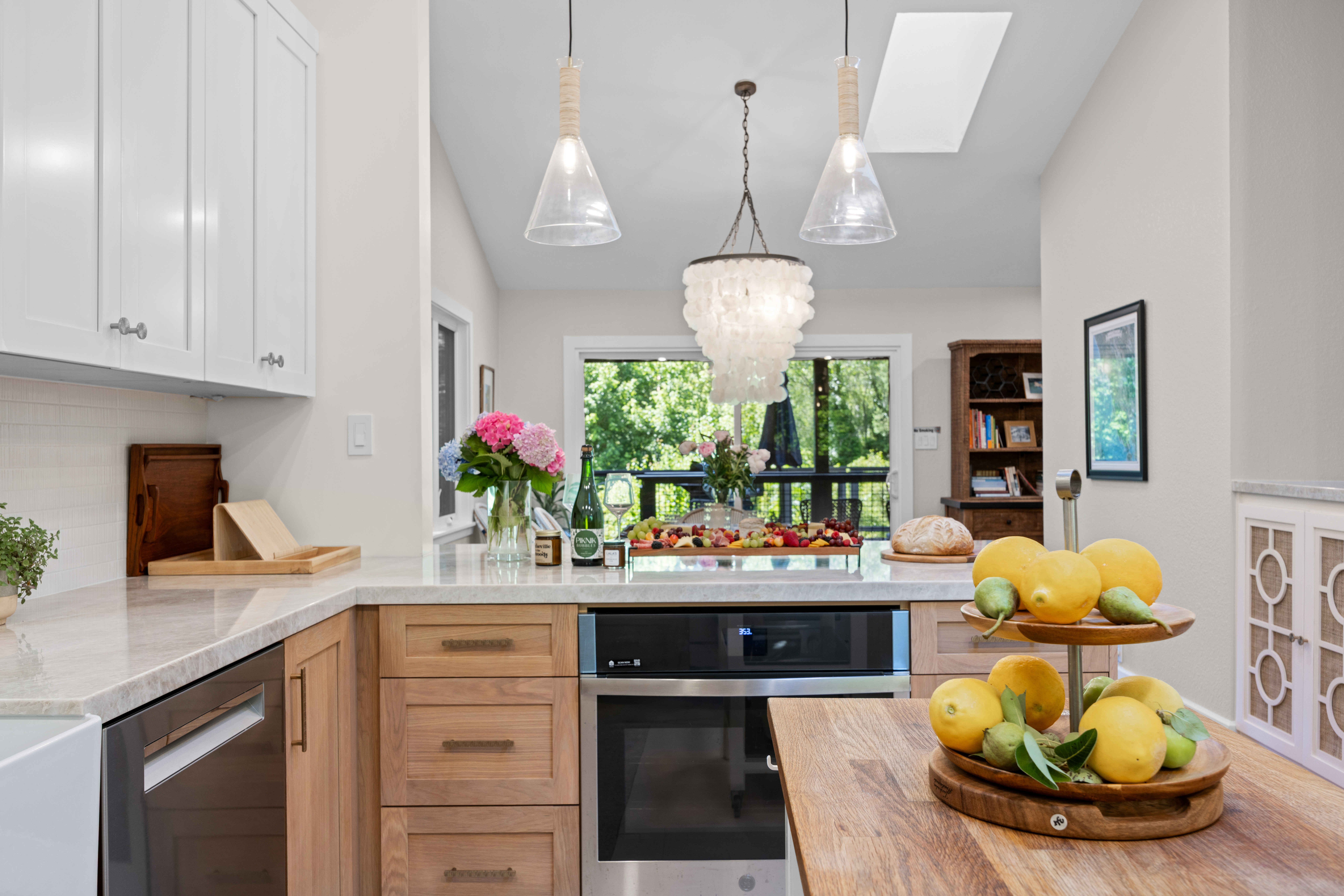 Bright designer kitchen with island, skylight, and lush outdoor views