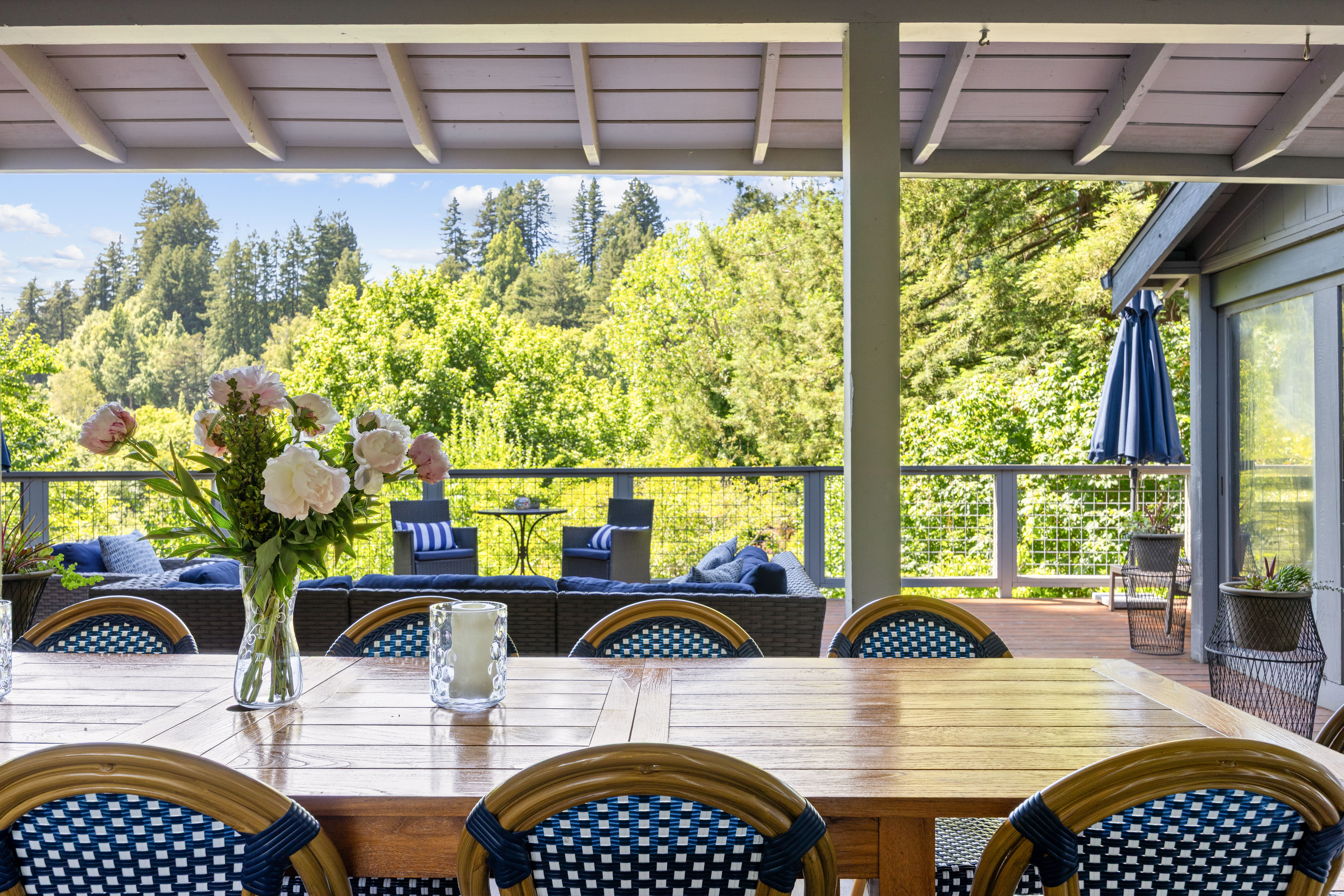 Covered deck dining and lounge space with serene forest views