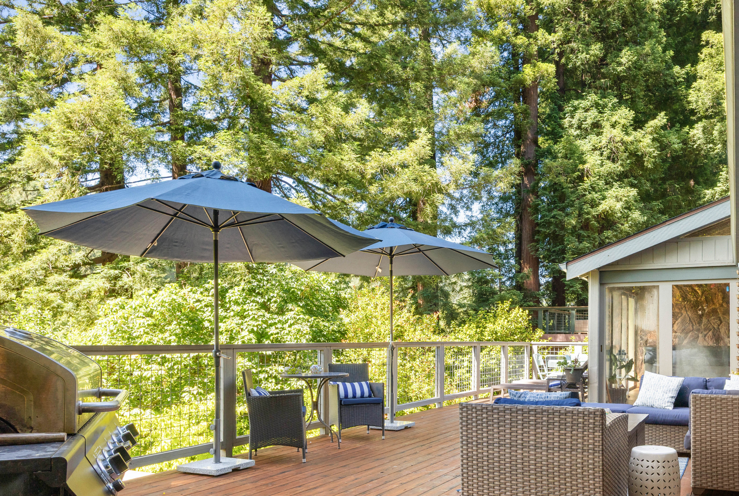 Private forest-view deck with lounge seating, umbrellas, and grill
