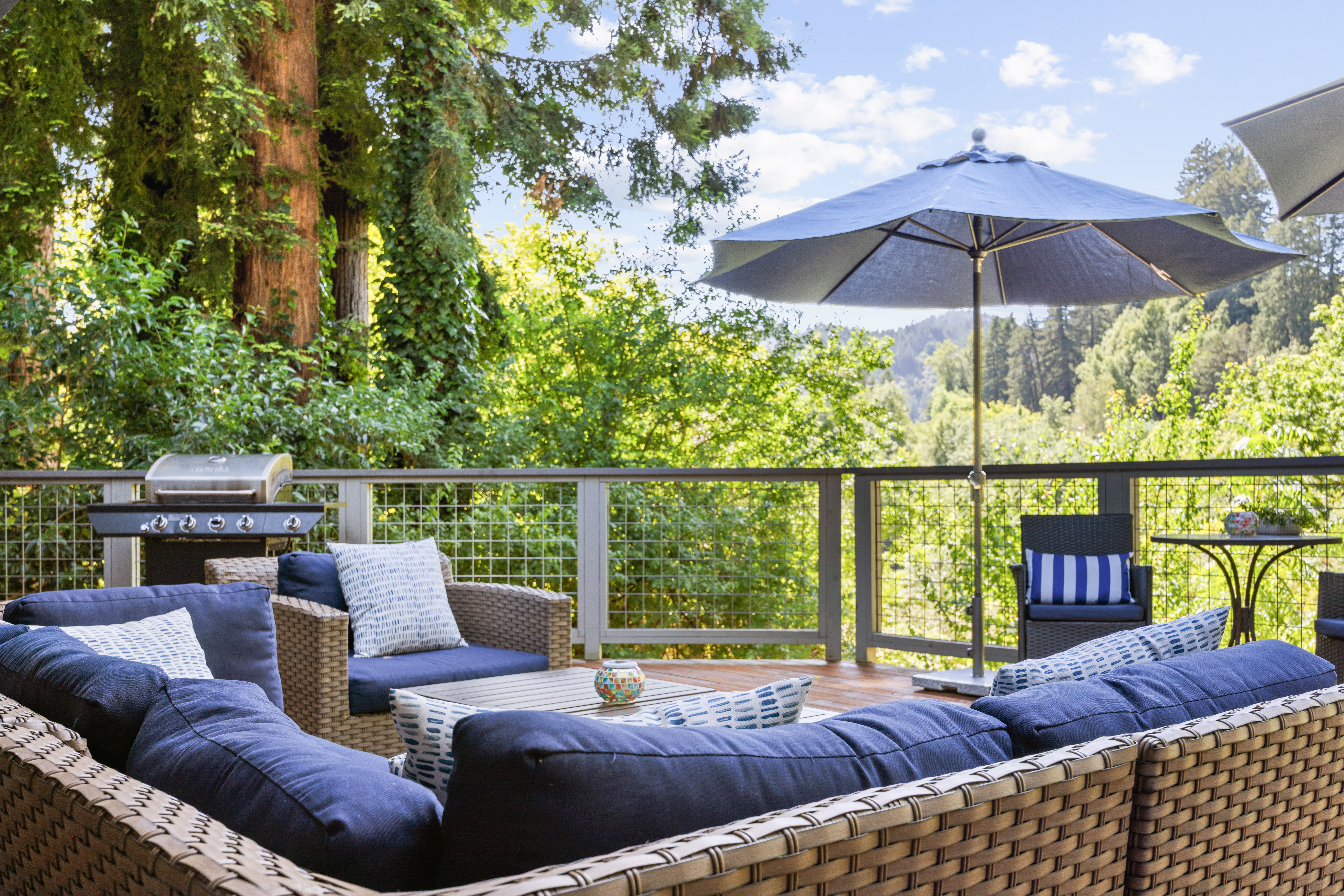 Private forest-view deck with plush seating, grill, and shaded lounge area